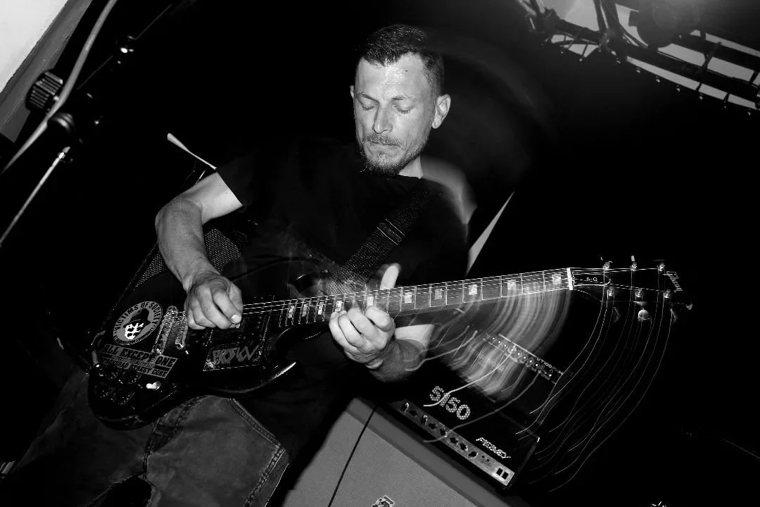 Man playing electric guitar in a dimly lit setting with motion blur effects.