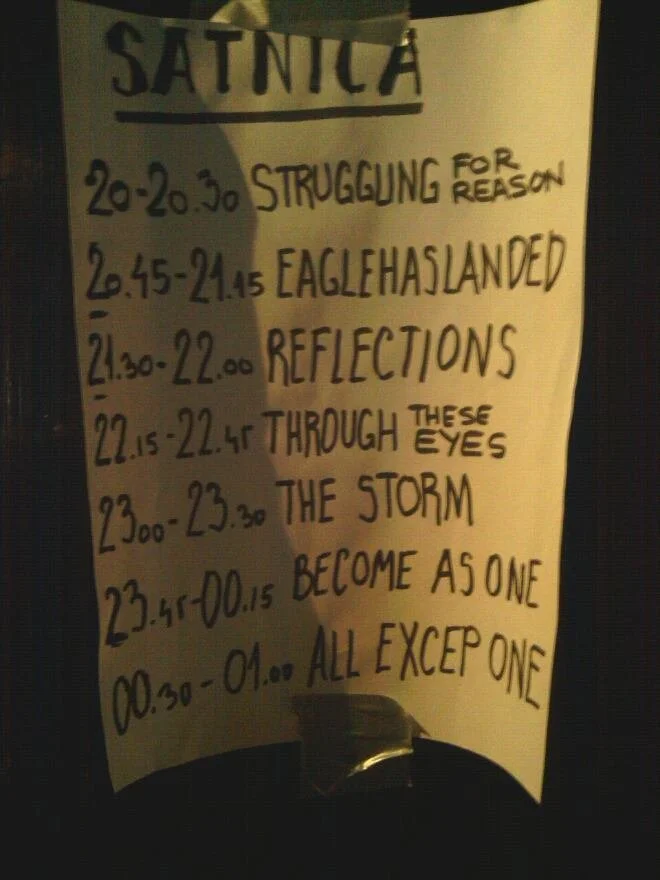 A handwritten schedule or program on a yellow paper, listing various time slots and titles such as 'STRUGGLING FOR REASON,' 'EAGLE HAS LANDED,' 'REFLECTIONS,' 'THROUGH THESE EYES,' 'THE STORM,' 'BECOME AS ONE,' and 'ALL EXCEPT ONE.' The schedule appe