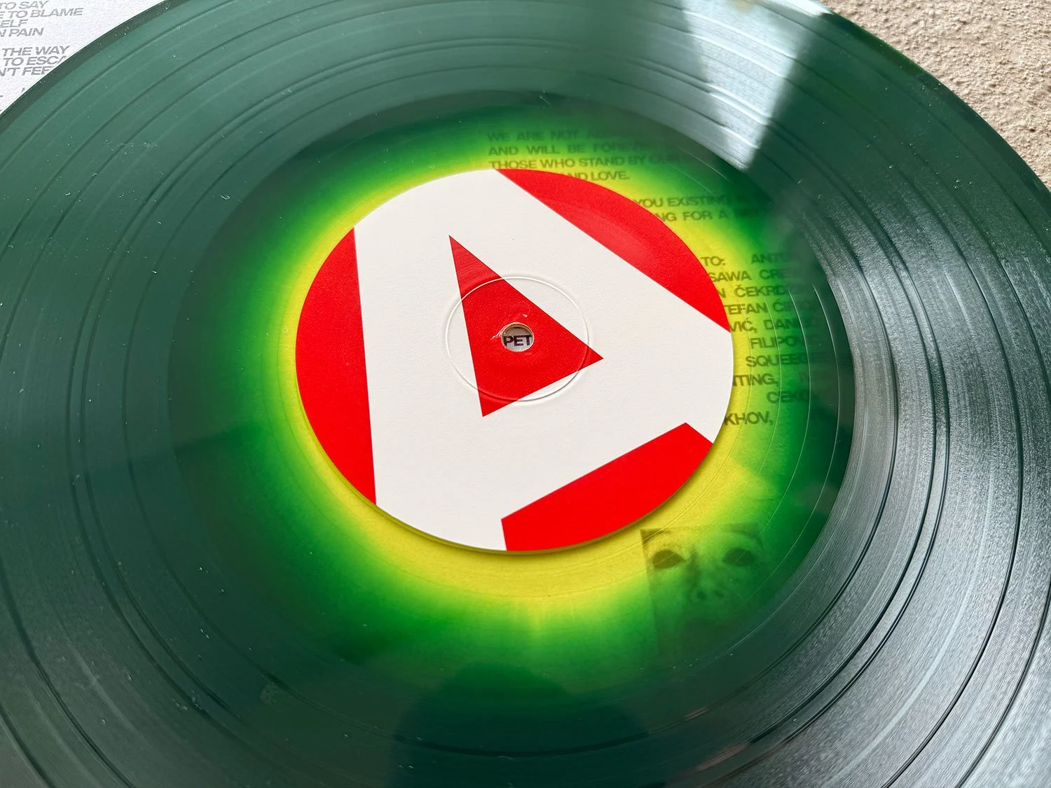 A vinyl record with a YouTube logo sticker in the center, surrounded by a green gradient overlay, with some faint text from the record label visible.