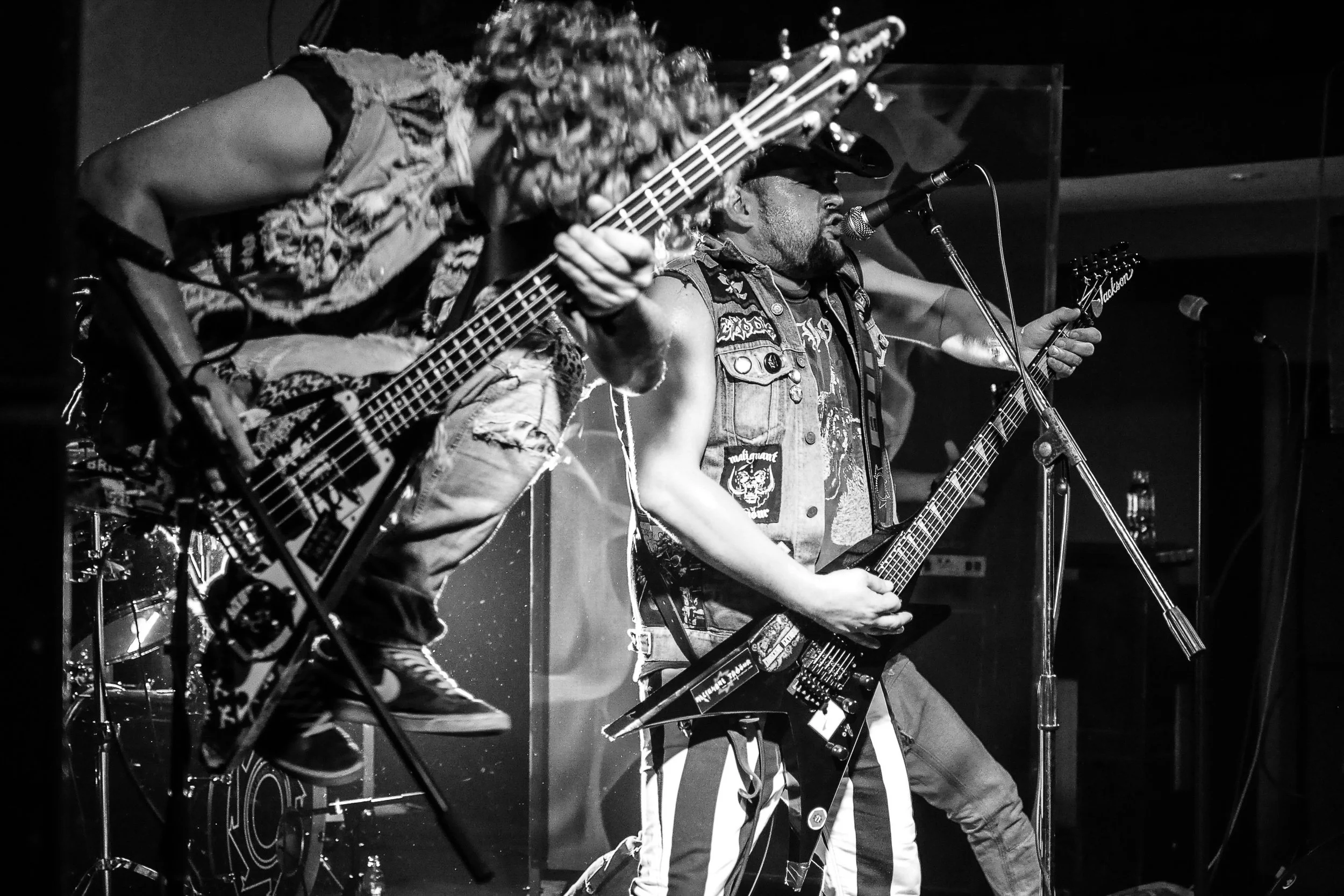 Musicians playing guitars on stage during a live performance, black and white photo.