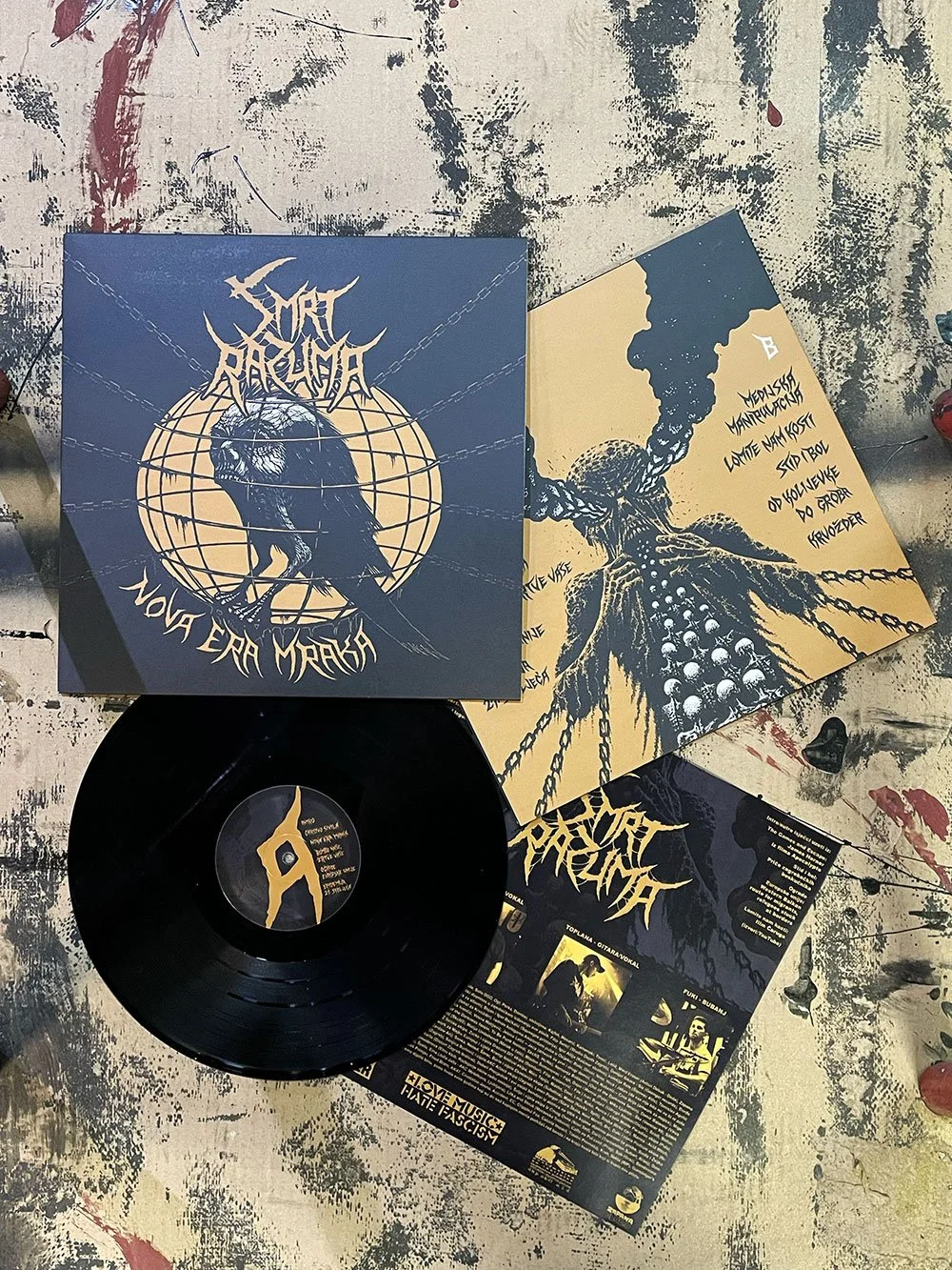 A vinyl record album and promotional materials for a band or music project titled "Nova Era Mraka" with dark, graphic artwork featuring a bird and a figure with chains on a textured surface.