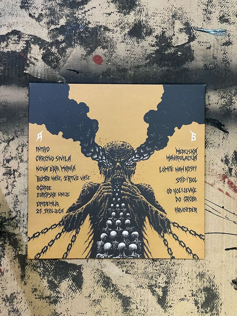 A poster with a black and beige illustration of a skull with smoke or clouds coming out from the top, and a row of skulls forming a pathway below. The poster has handwritten-style text in Croatian with titles and information.