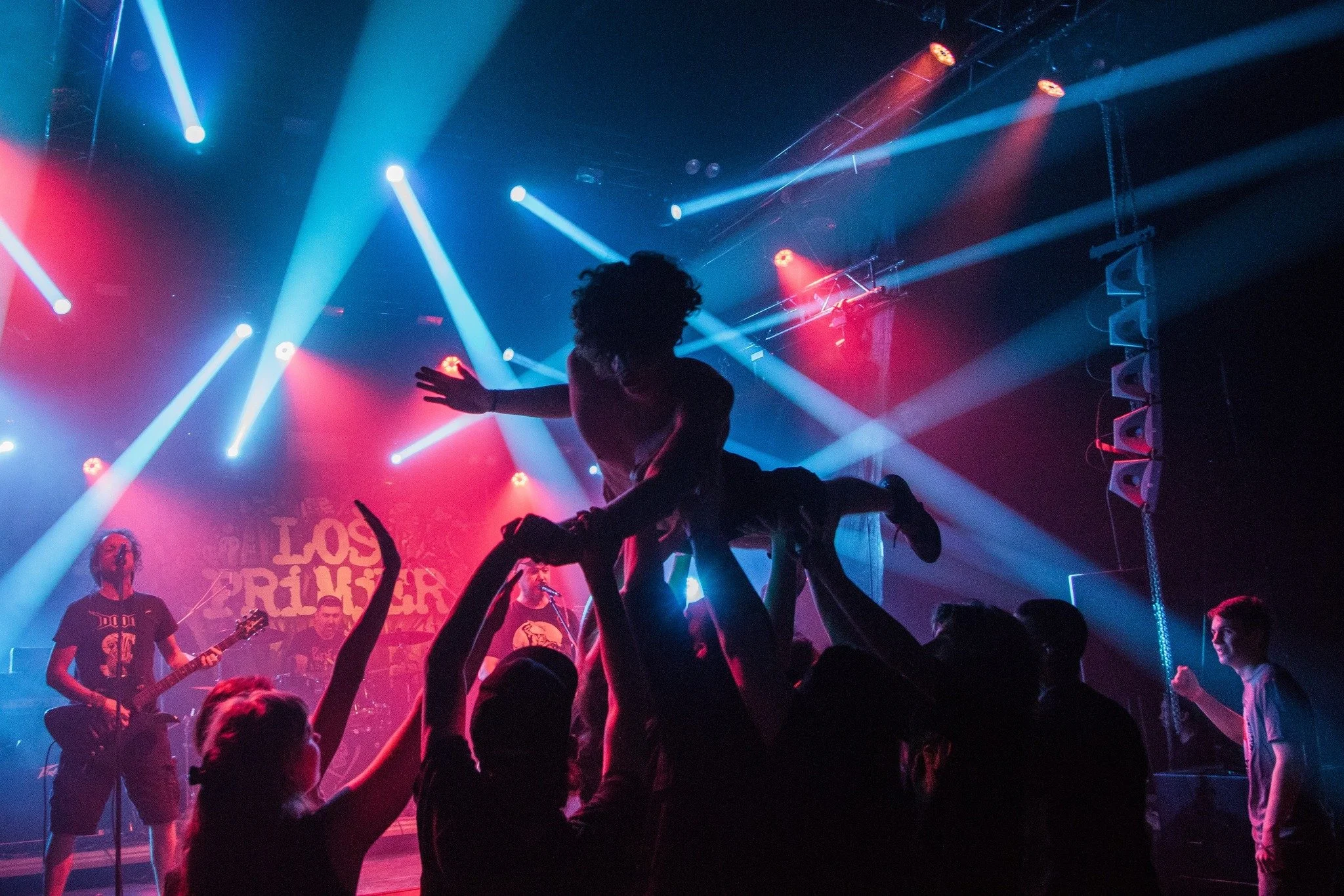 A concert scene with a band performing on stage, colorful lights, and an audience dancing.