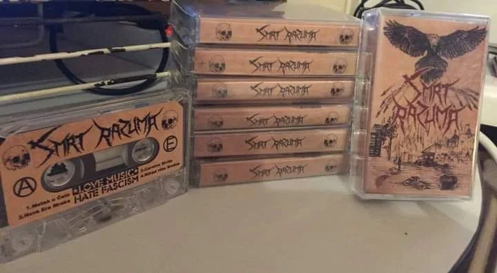 Multiple cassette tapes and a cassette case with album art on a table.