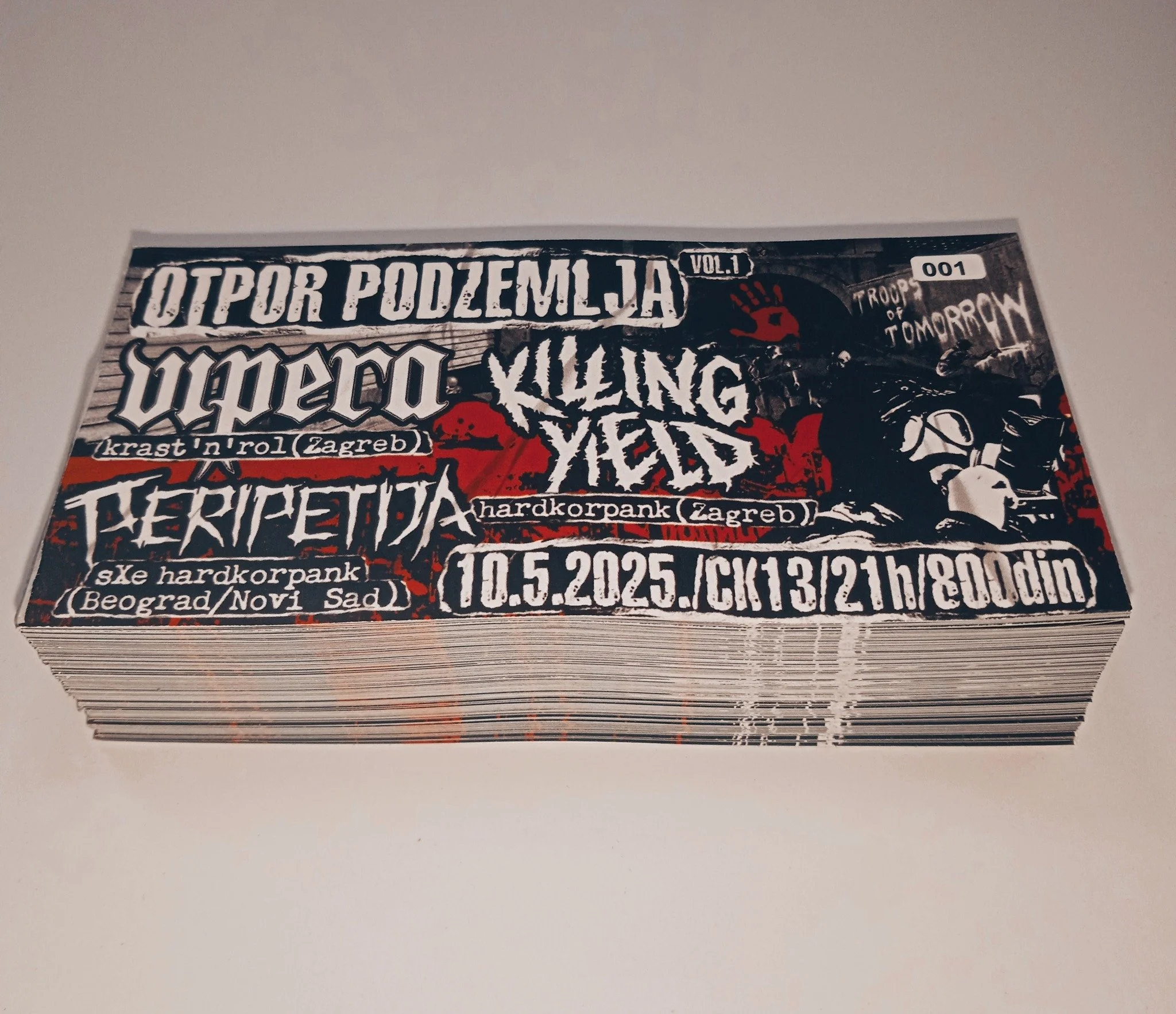 A stack of concert tickets or event passes featuring dark artwork with bold white and red text, including references to hardcore punk bands and locations such as Zagreb, with a date of May 10, 2025.