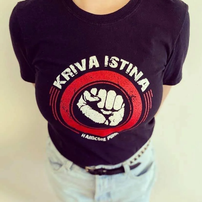 Person wearing a black T-shirt with a red and white graphic design featuring a clenched fist and the text "KRIVA ISTINA" and "HARDCORE PUNK".