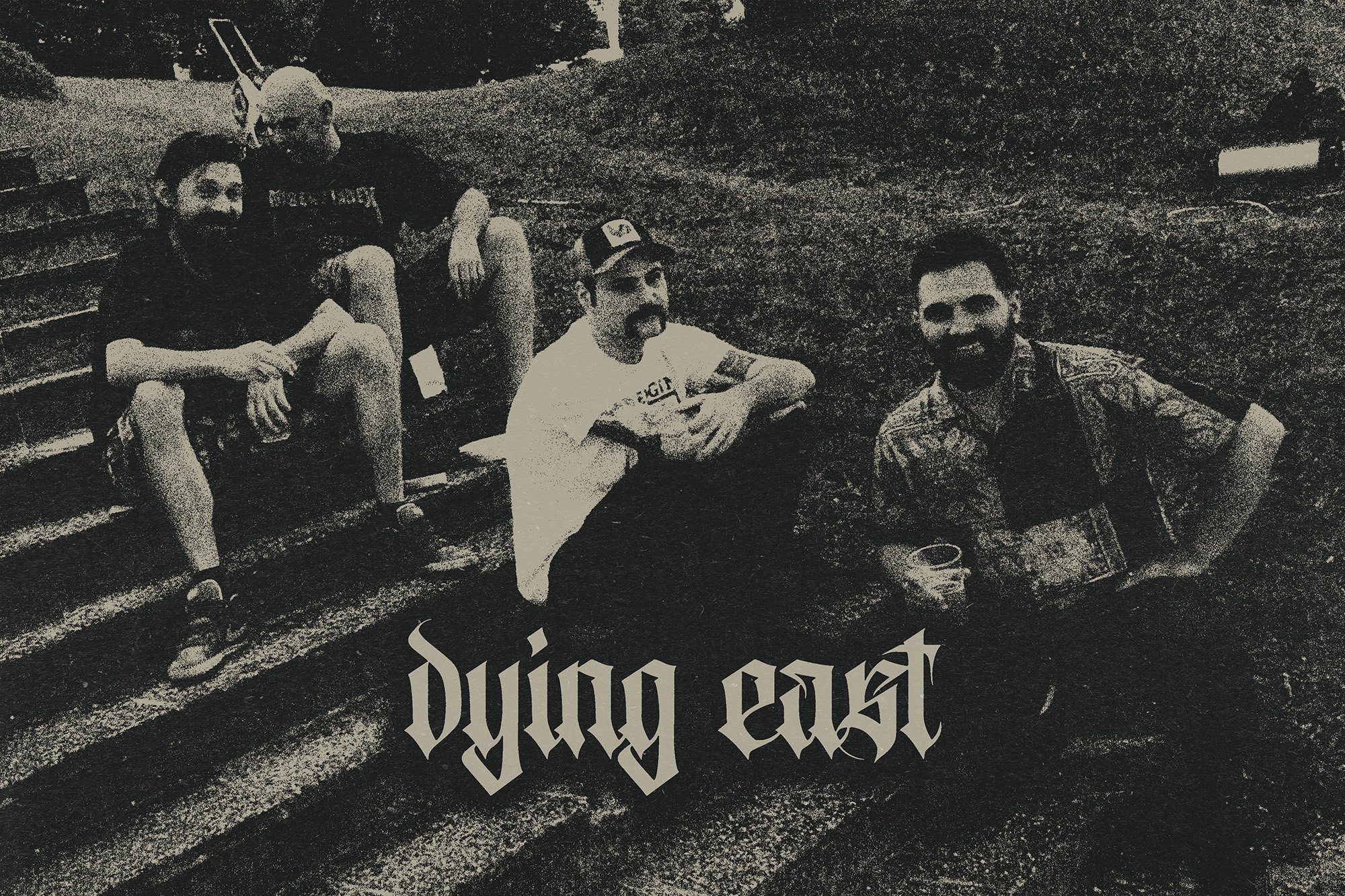 Four men sitting on outdoor stadium bleachers before their show appearance as band DYING EAST.