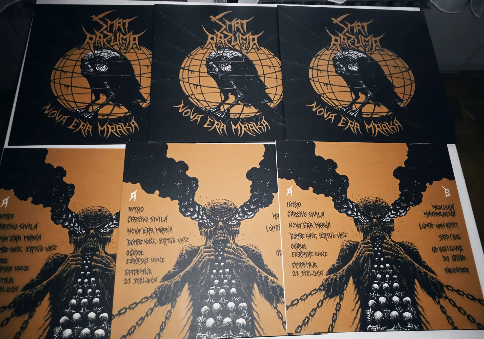 Multiple posters featuring a black and orange illustration of a volcano erupting with smoke and lava, including text with a list of song titles and a band name, 'Smrt Razuma'.