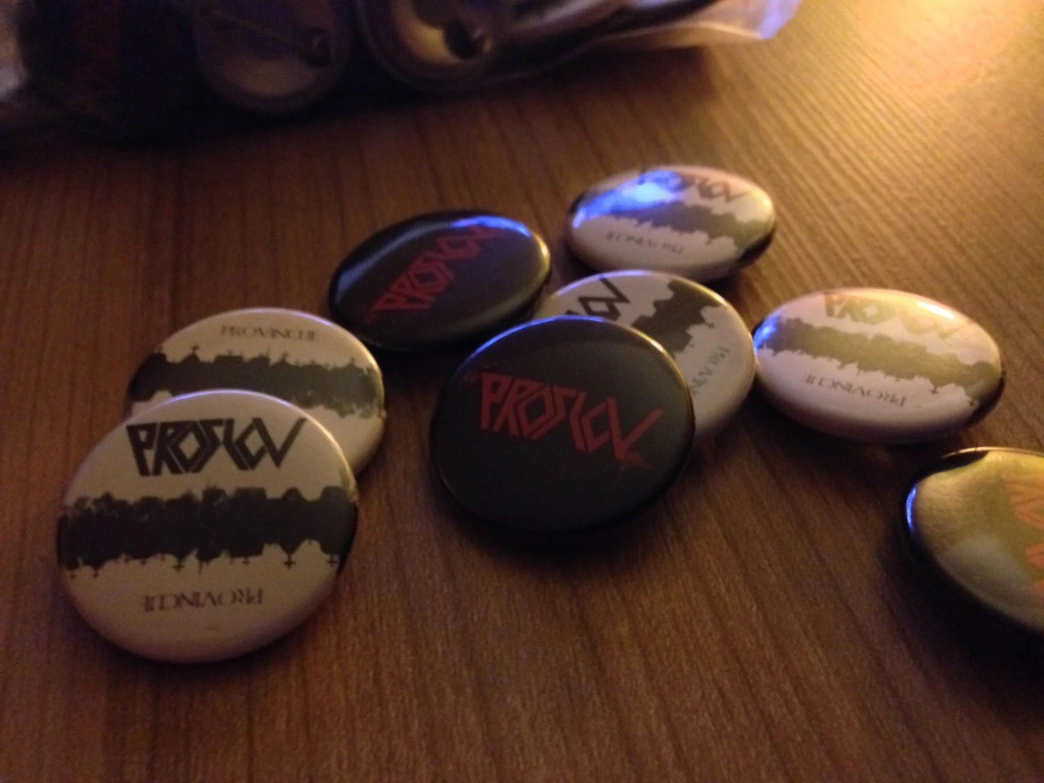 Clothing buttons with various designs, some with world map and others with text, scattered on a wooden surface.