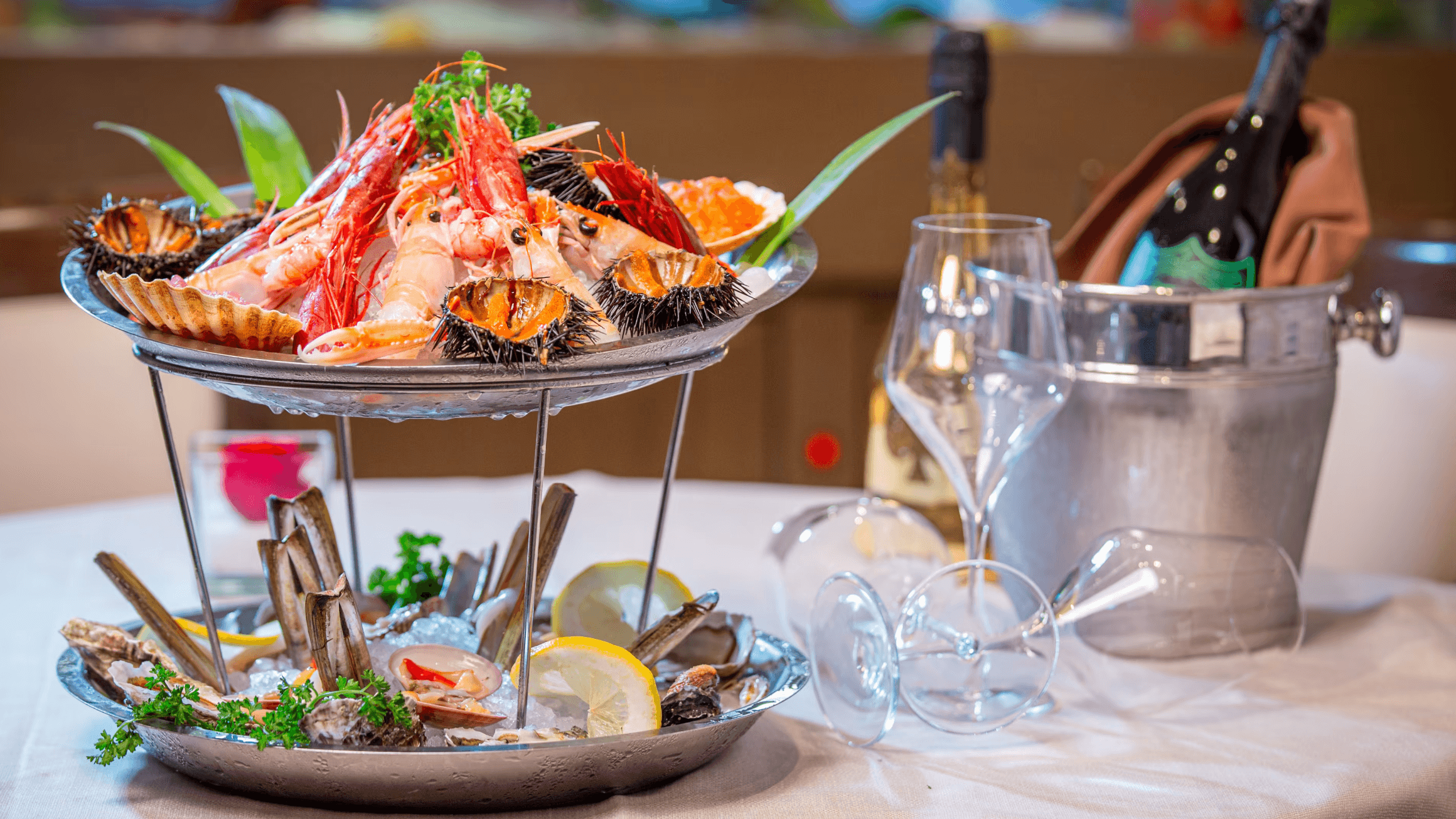 Assortimento di frutti di mare su un vassoio di metallo con limoni e prezzemolo, con una bottiglia di vino e bicchieri sul tavolo
