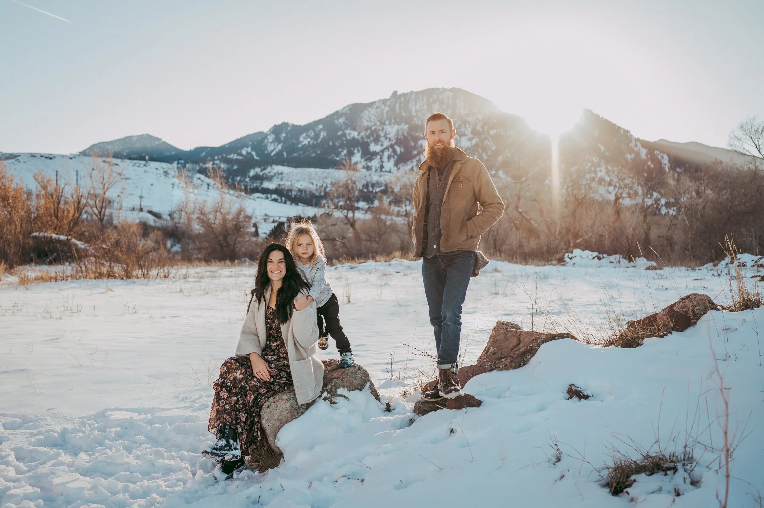 Family smiling in front of snowy mountains in Boulder, Colorado