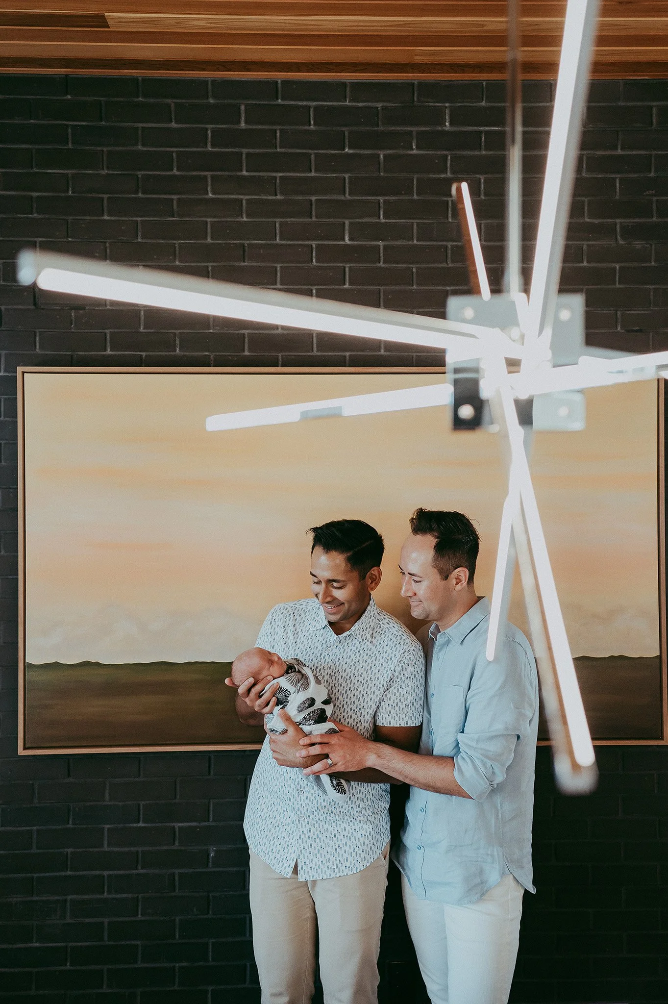 Gay couple with newborn baby in modern home. 