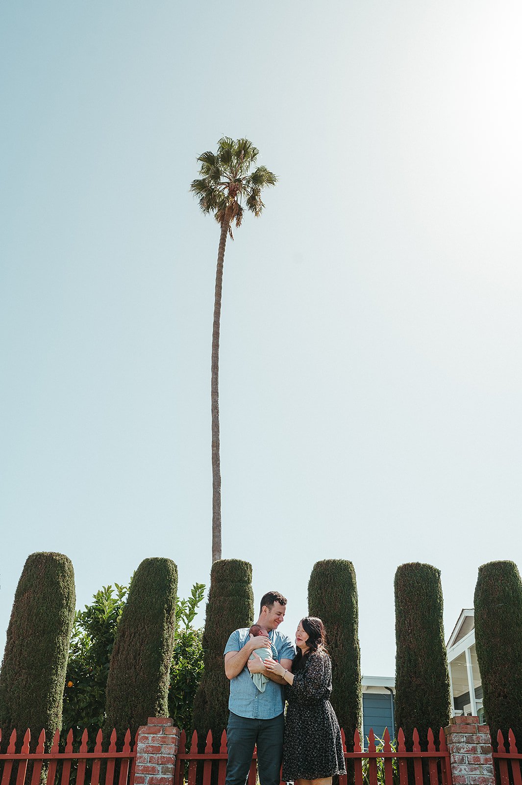 Family and baby smiling in front of palm tree in San Jose, California. 
