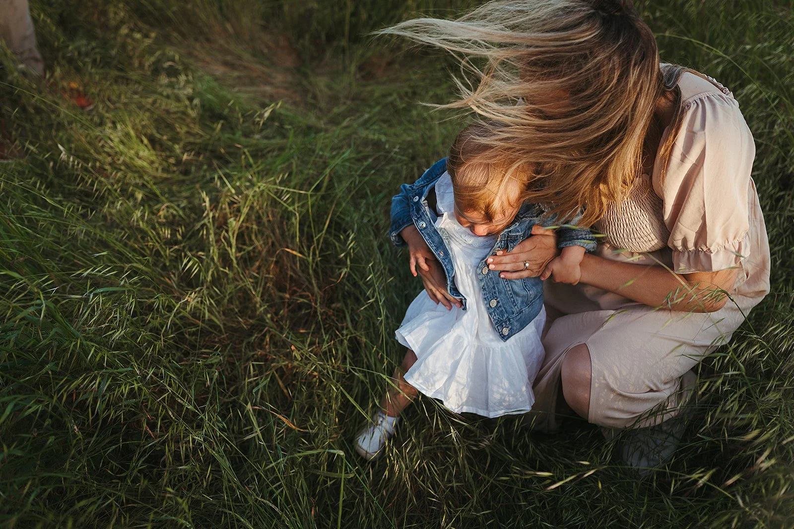 Mother's hair blowing in the wind while holding toddler in Sonoma, California. 