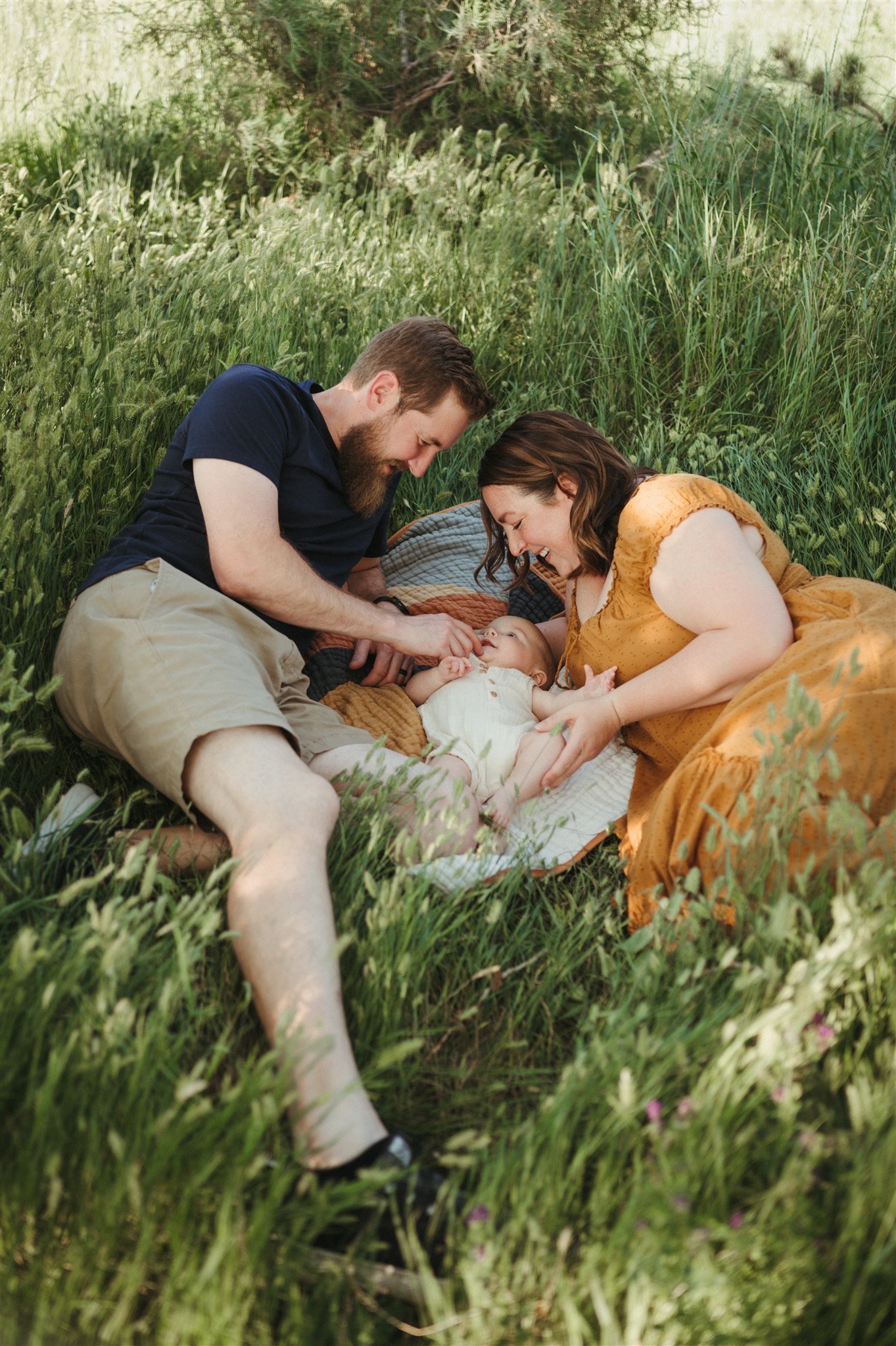 Parents lying in field with newborn baby in Boulder, Colorado. 