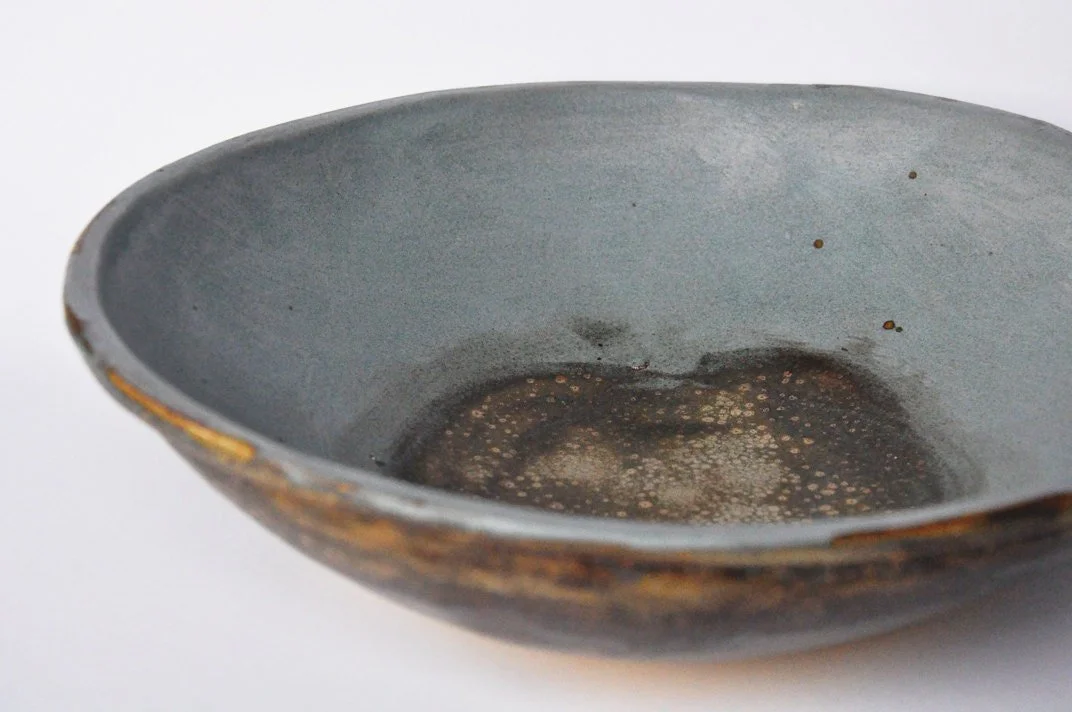 A close-up of an empty ceramic bowl with a worn, rustic appearance.