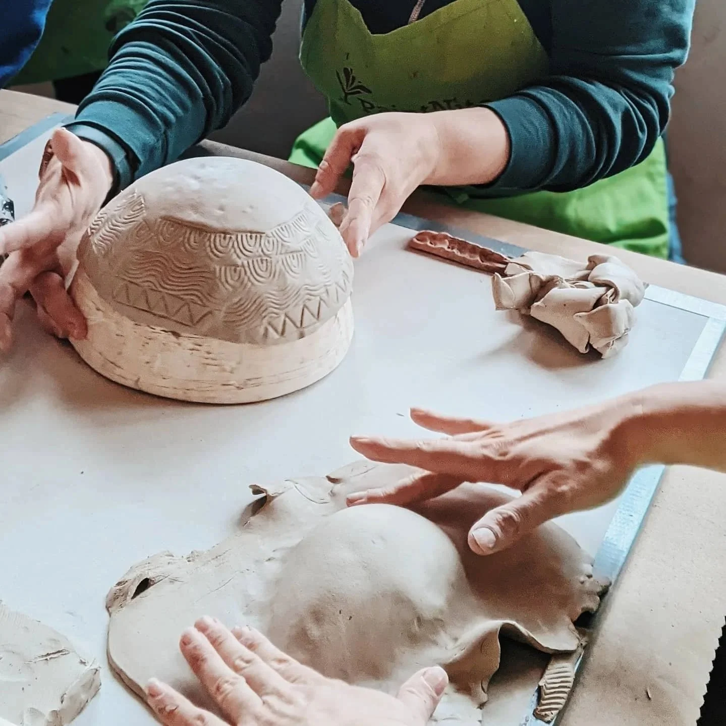 hands forming clay bowls at a workshop
