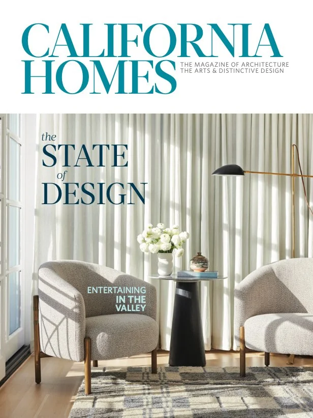 Cover of California Homes magazine featuring a modern living room with two beige armchairs, a small round black side table with a flower vase, plush curtains, and a tall black and brass floor lamp, with the title 'California Homes' and the headline '