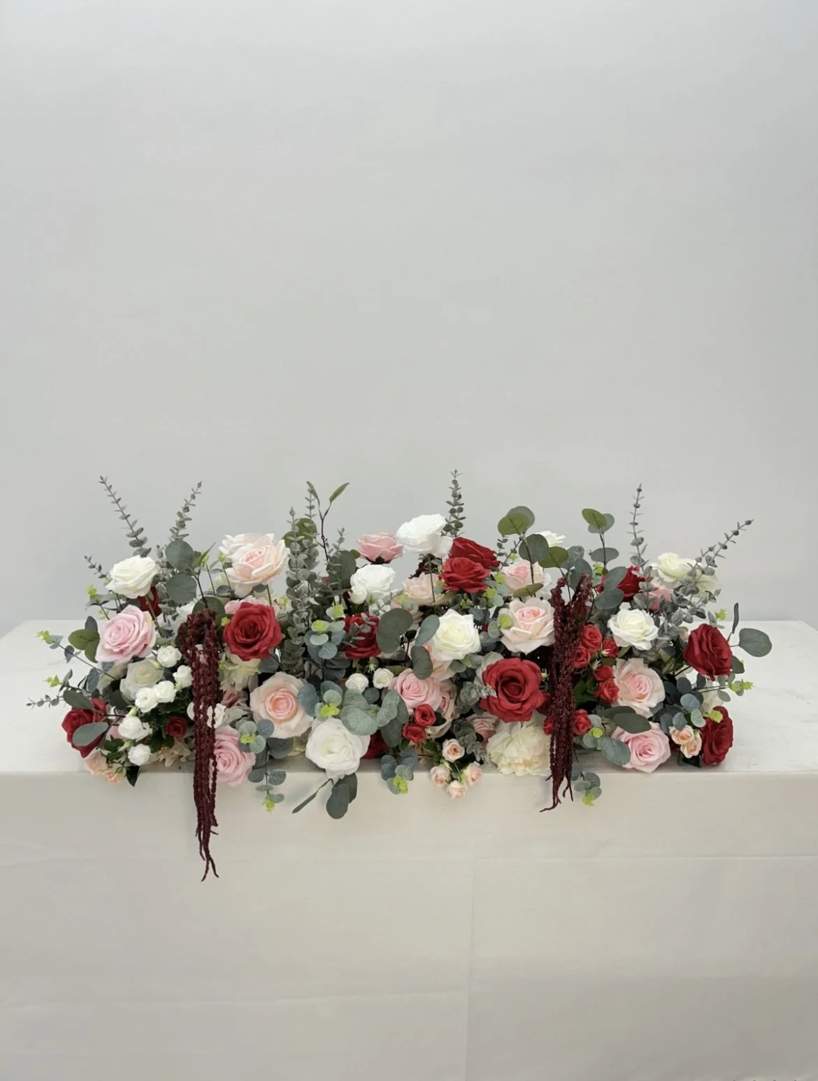 Arranged floral display with roses and greenery on a white surface.