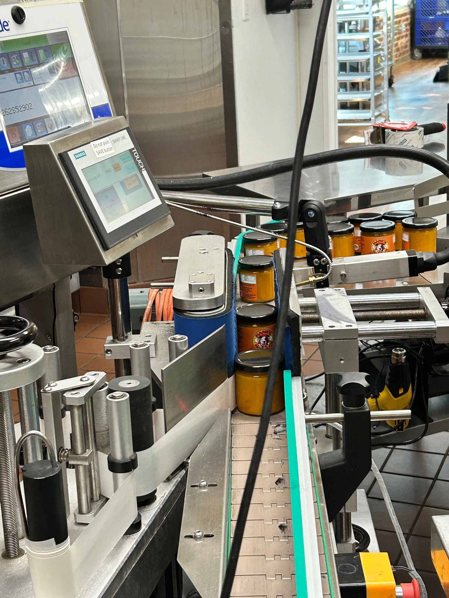 Jars of mustard or sauce on an industrial food production line conveyor belt.