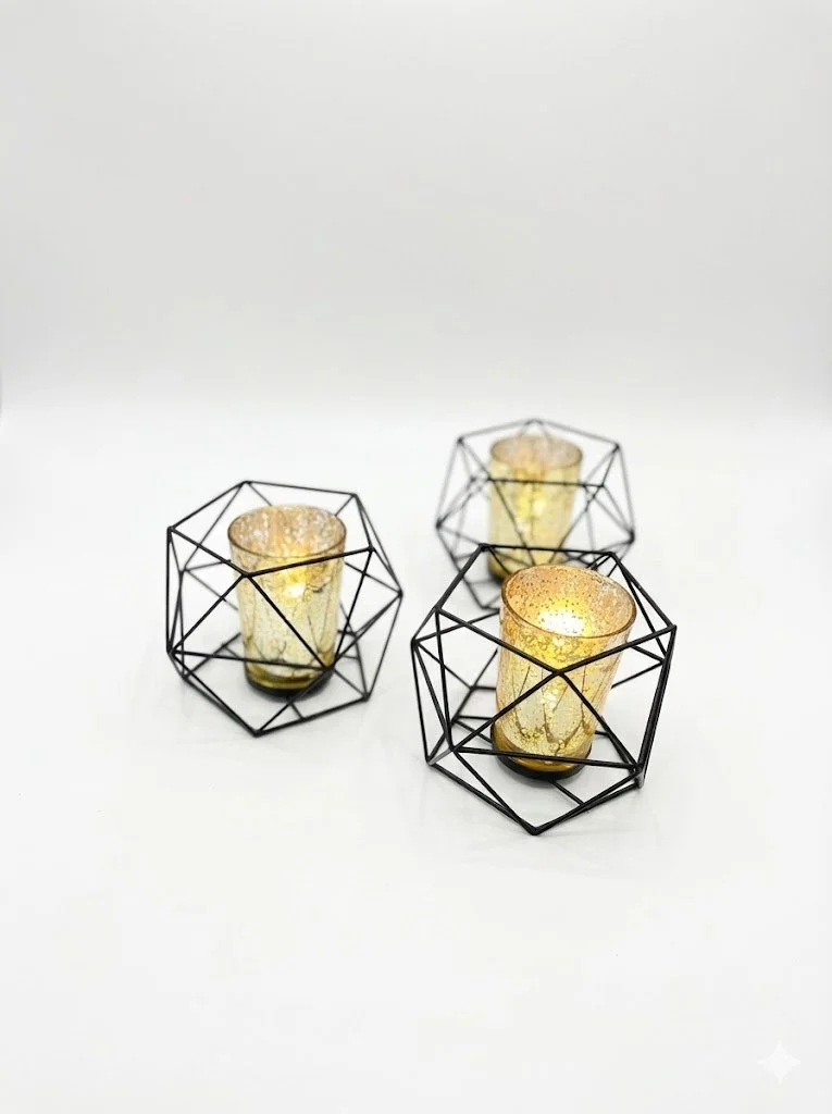 Three decorative candle holders with black wire geometric frames, each holding a gold-tinted candle with a textured surface, on a white background.
