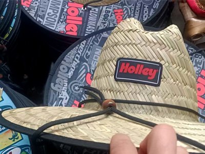 A straw cowboy hat with a black chin strap and a red and black 'Holley' logo on the front.