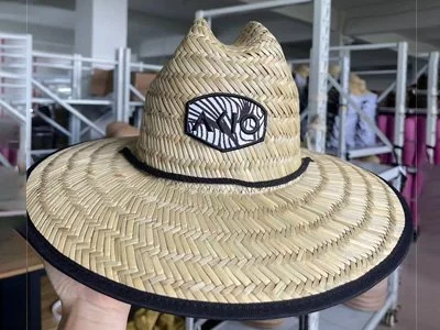 A wide-brimmed straw hat with a black band and a logo patch on the front.