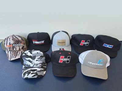 Eight baseball caps with various colors and logos, arranged on a flat surface against a plain background.