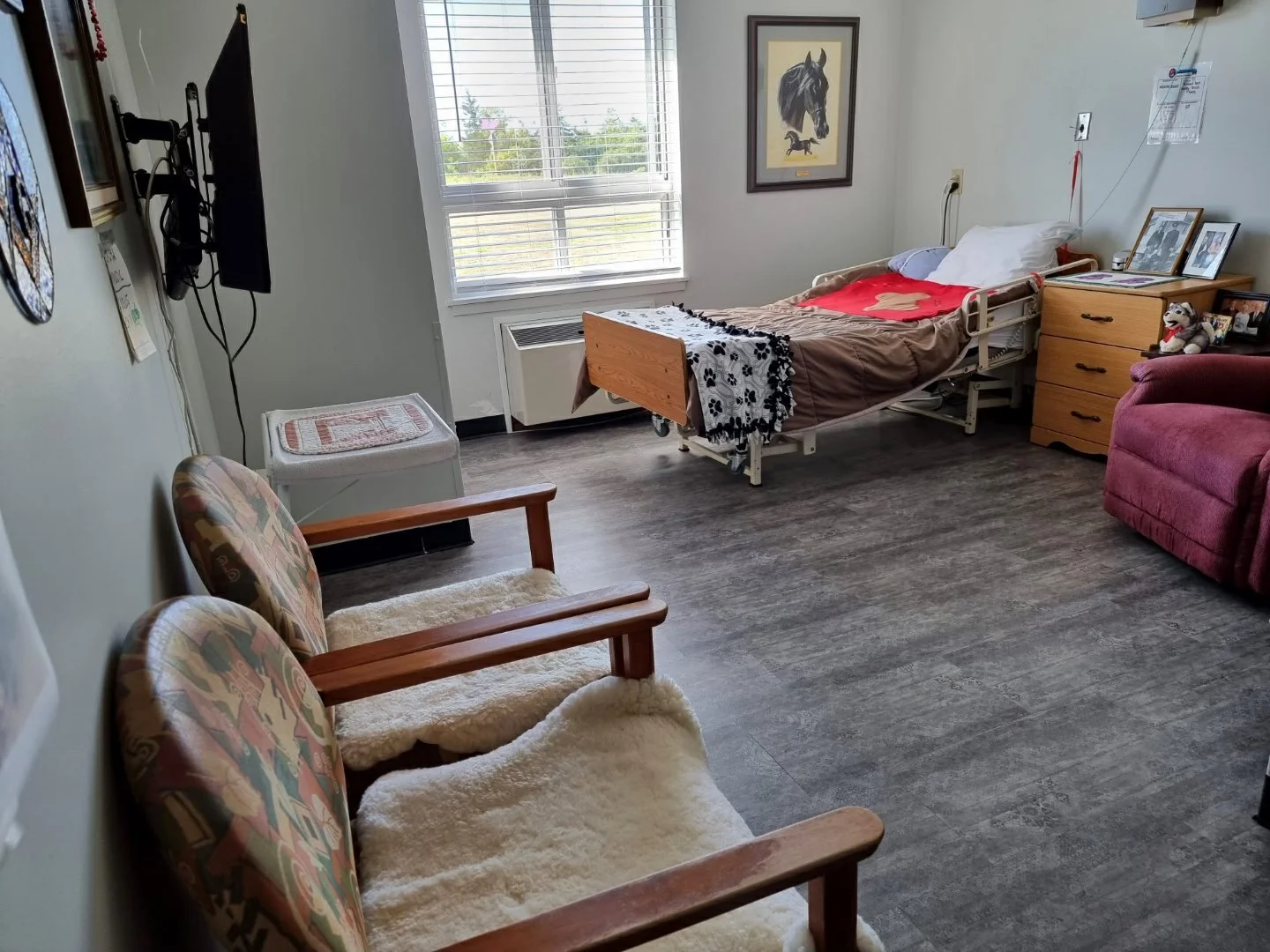 A hospital room with a bed, chairs, window, and various personal items and decorations.