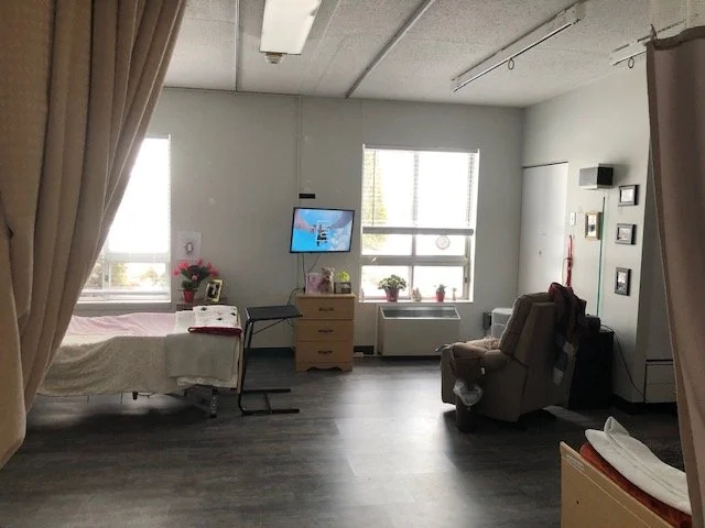 Hospital room with bed, flowers, TV, and armchair