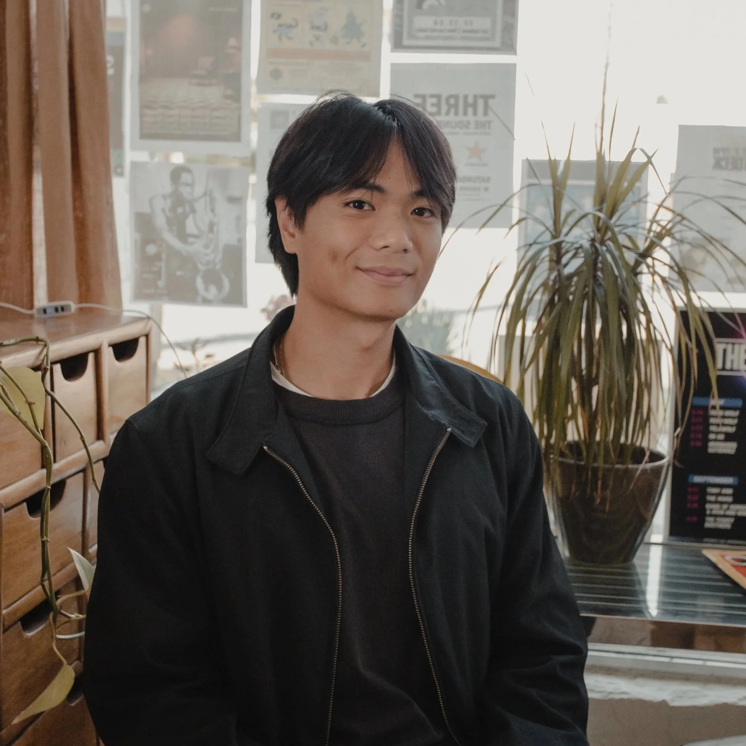 Man sitting at a table wearing a jacket and smiling.