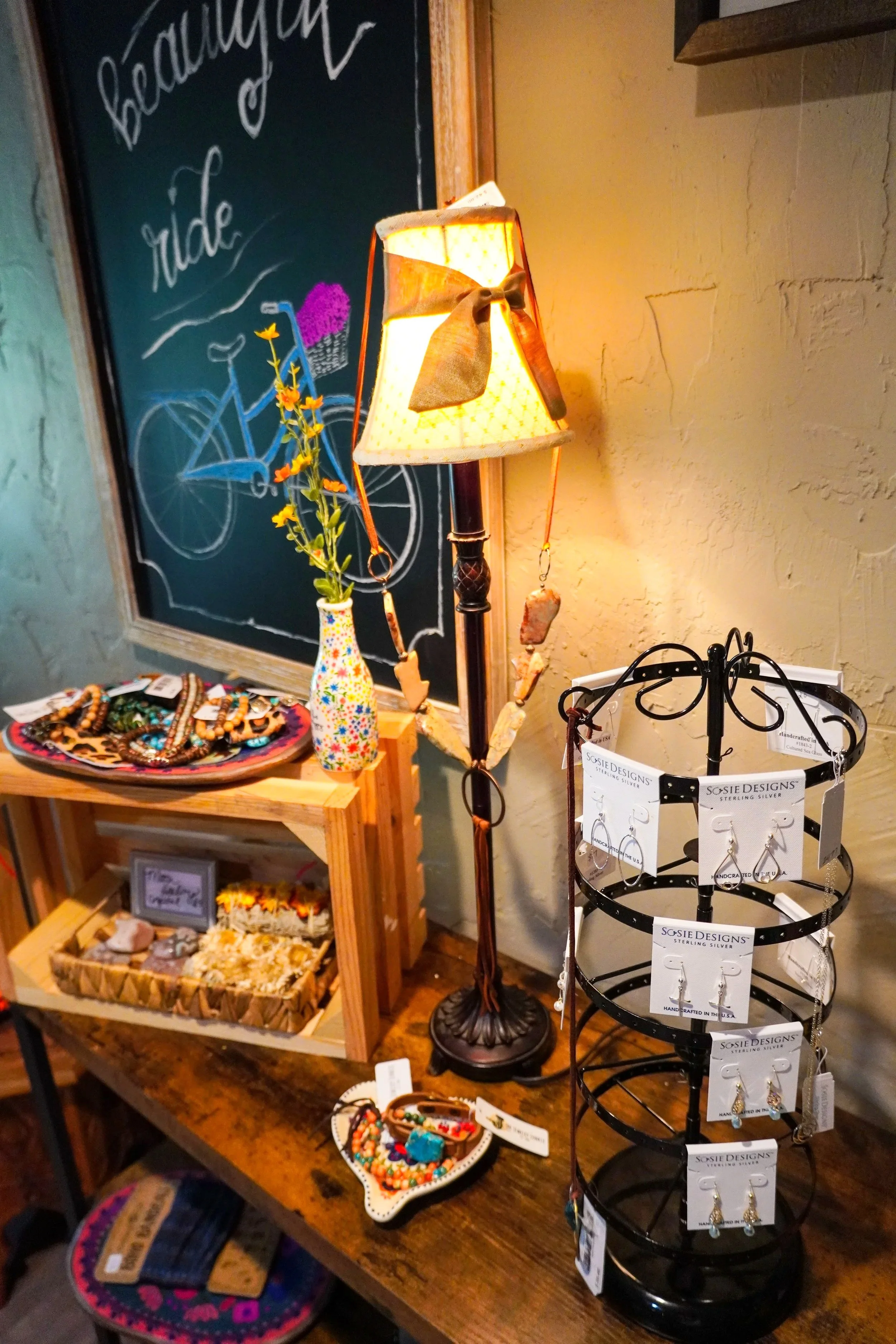 Table displaying jewelry and accessories, including earrings, bracelets, and necklaces, with a decorative lamp in the center.