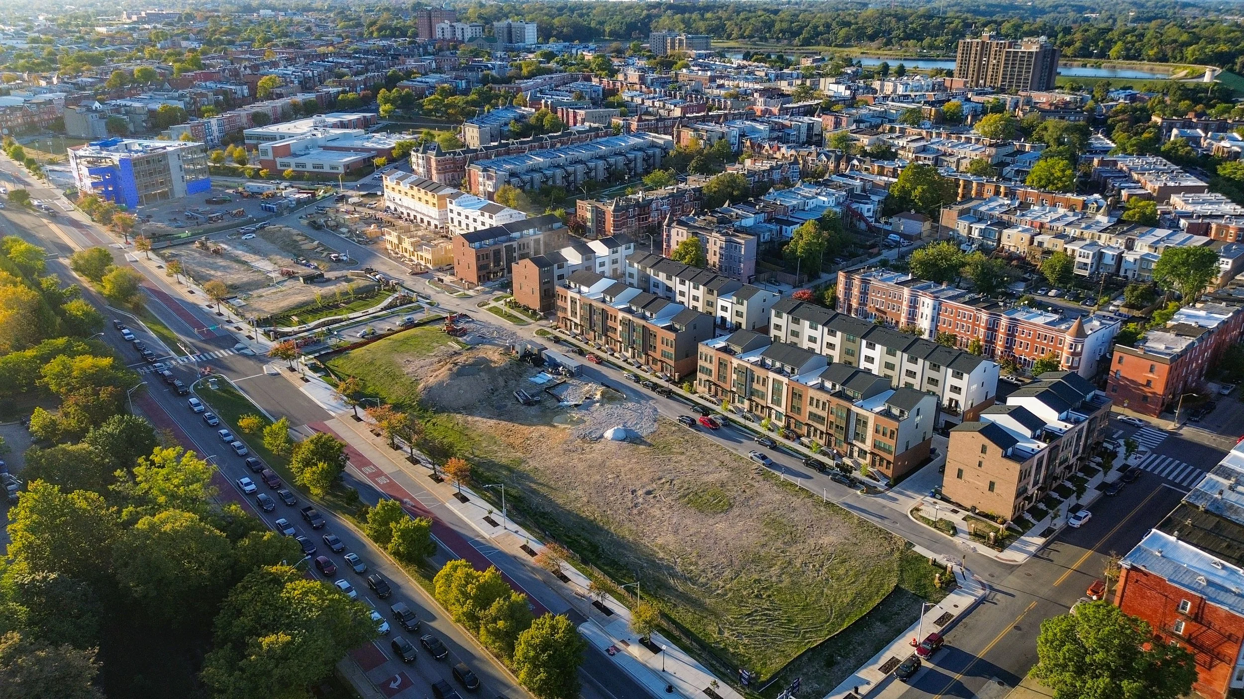 Aerial view of a city neighborhood with new construction, modern townhouses, and streets lined with trees.