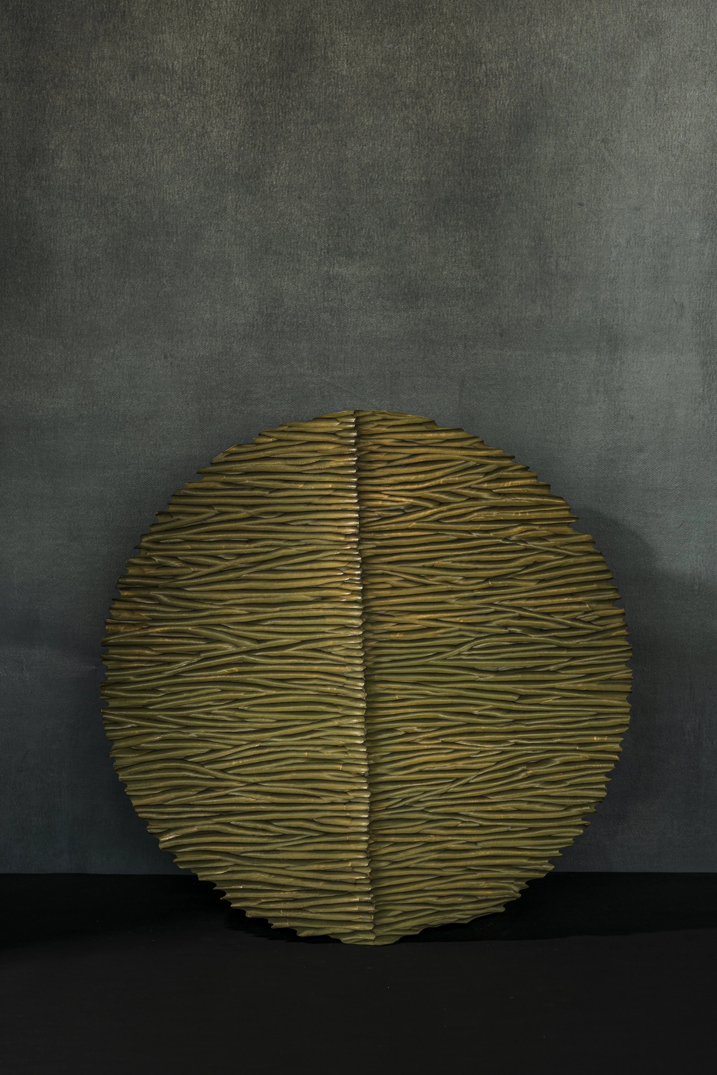 Rundes Wandrelief mit gefräster Struktur und grüner Farbe.