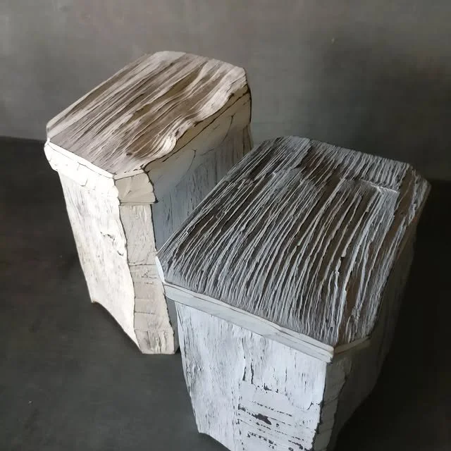 Zwei Holzskulpturen, die wie stilisierte Stühle aussehen, aus alten, weißen Holzstücken gefertigt.