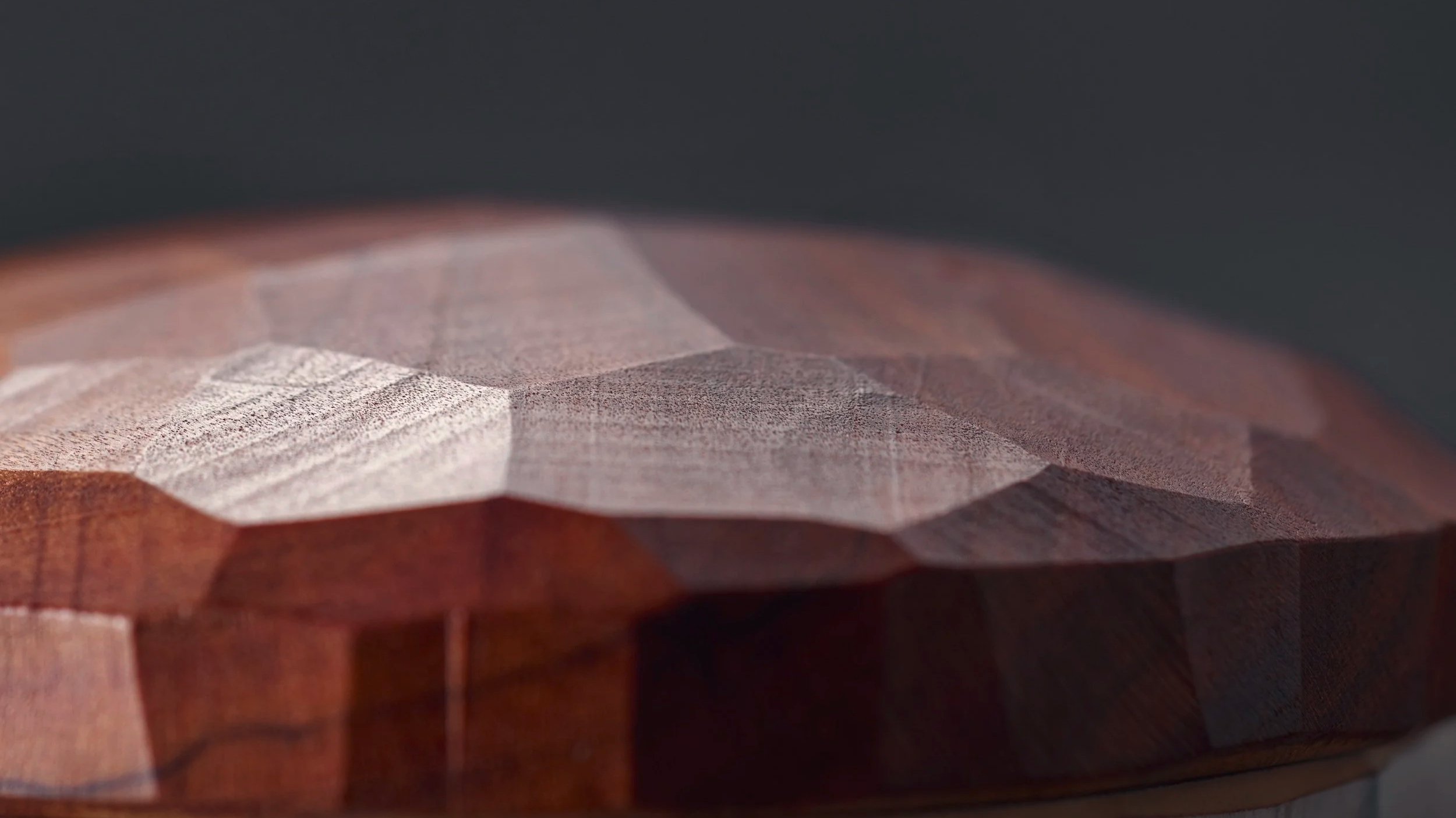 Nahaufnahme einer dekorativen Holzskulptur mit geometrischen Flächen und einer glatten, polierten Oberfläche