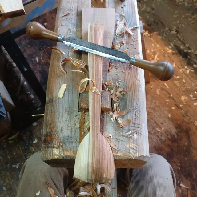 Holzarbeit mit einem Hobel und Holzspänen auf einem Werkstück auf einem Arbeitstisch in der Werkstatt.