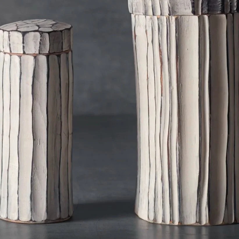 Zwei geschnitzte, weiß bemalte Holzdosen oder Urnen mit kanelierter Struktur.