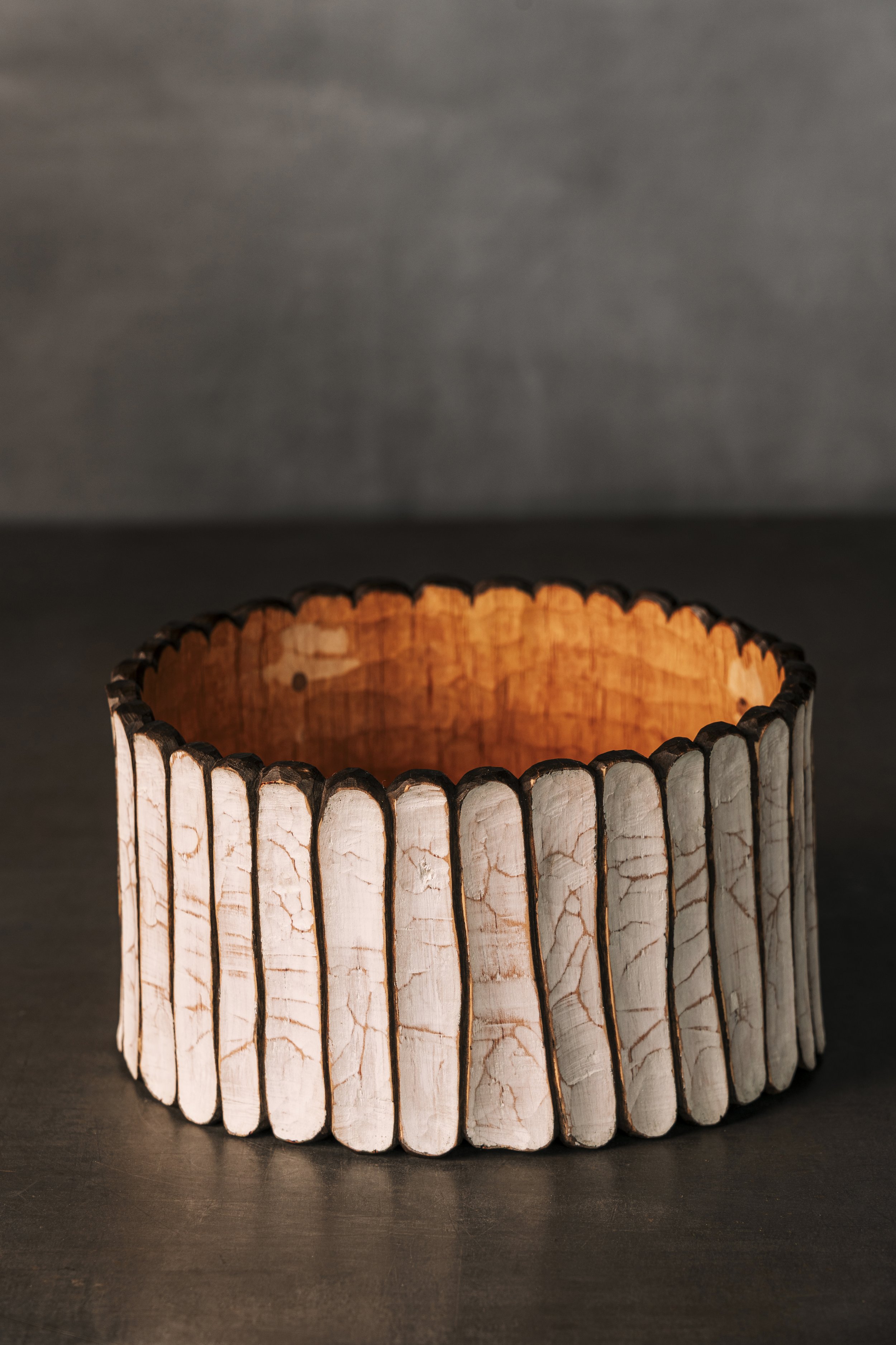 Rundes Holzgefäß mit geschnitzter kanelierter Struktur.