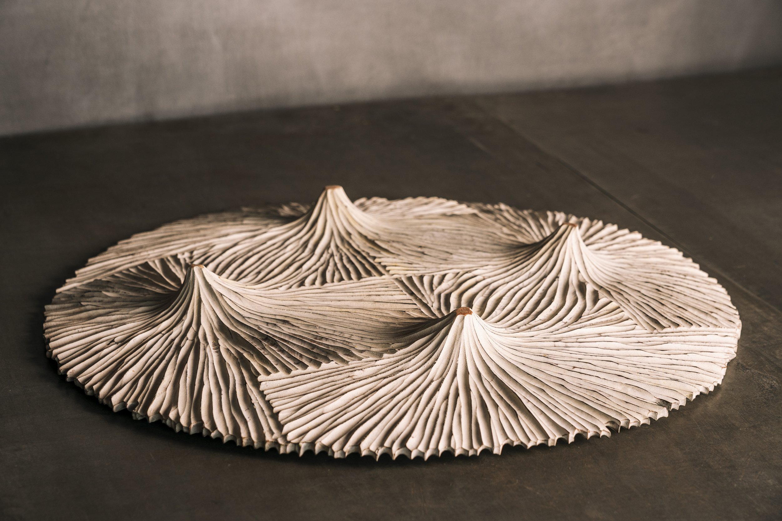 Kunstwerk aus mehreren Papierrollen, die in Wellenform gefaltet sind, auf einem dunklen Tisch