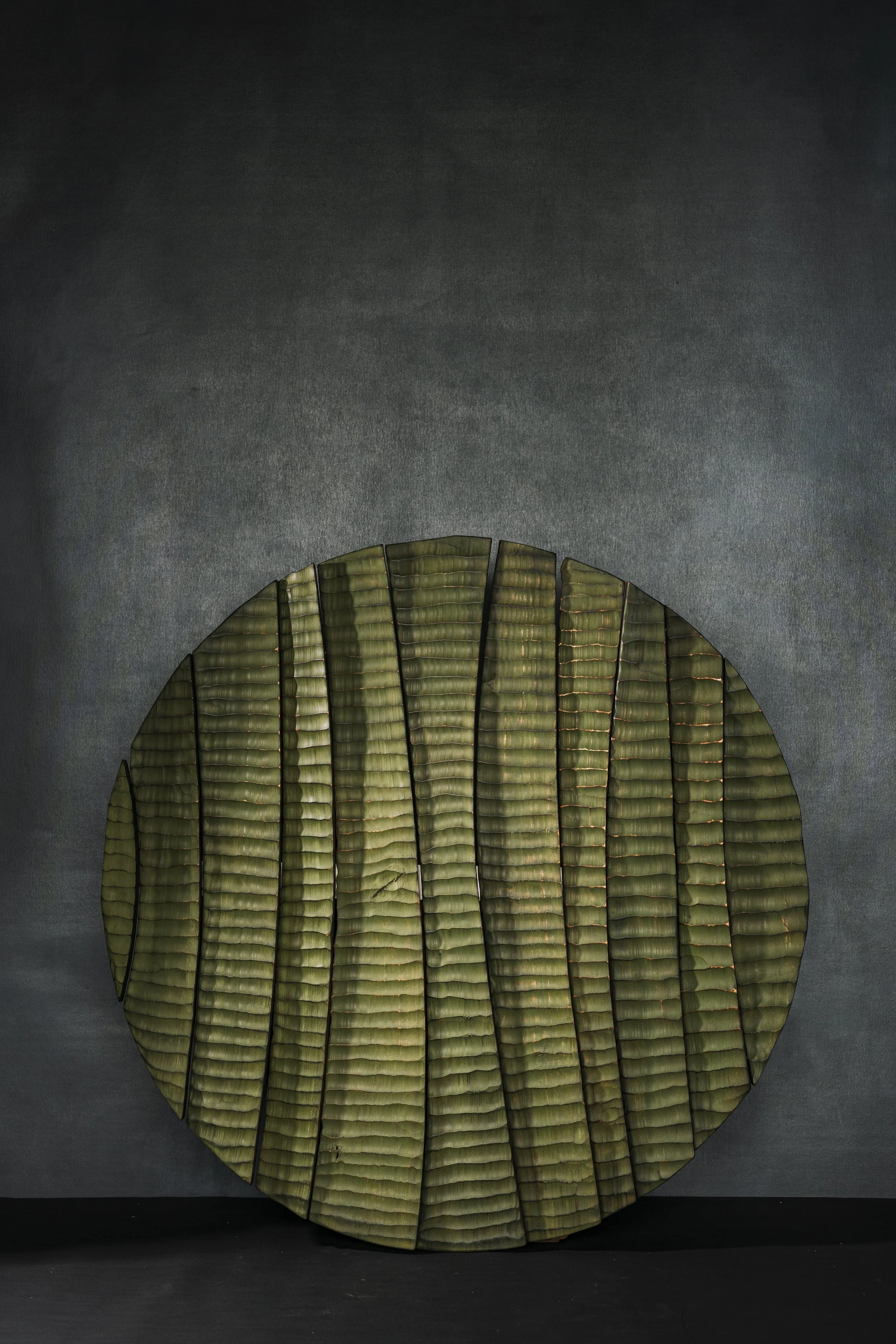 Rundes Wandrelief aus mehreren Teilen zusammengesetzt und grün bemalt.