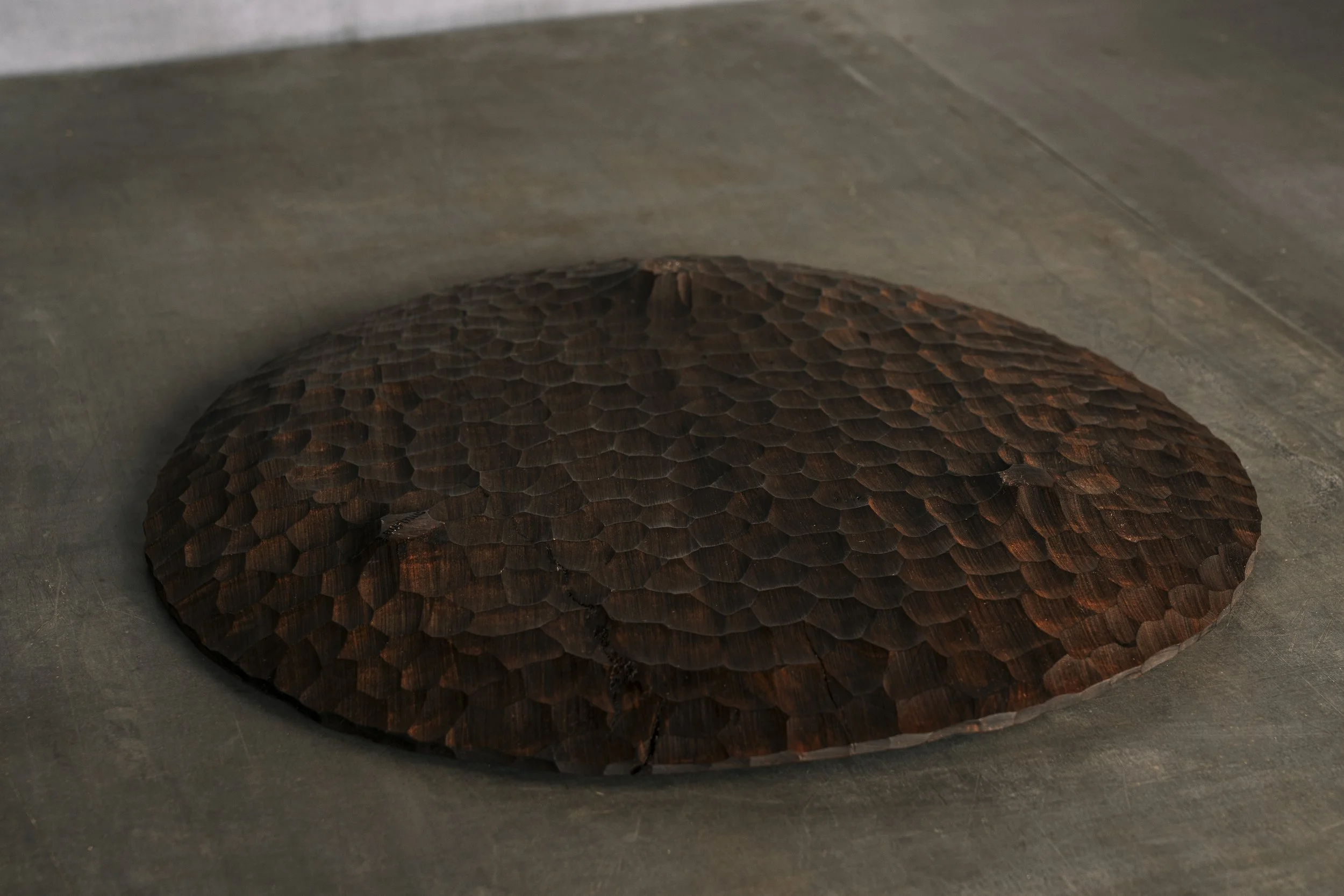 Unterseite einer flachen Holzschale mit drei Standfüßen.