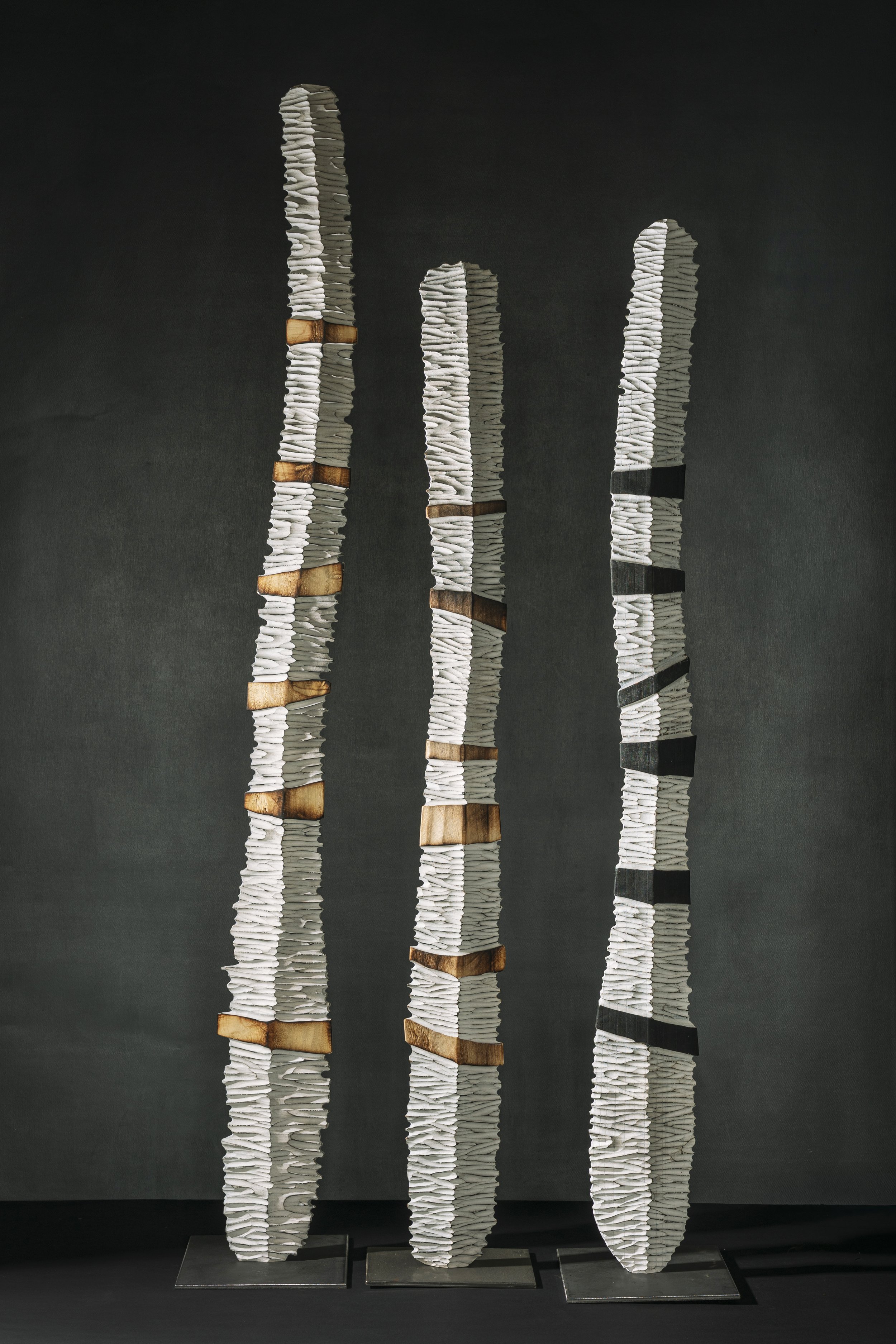 Drei Holzstelen mit geschnitzten horizontalen Rillen und Balken mit interessantewr Licht-Schattenwirkung.