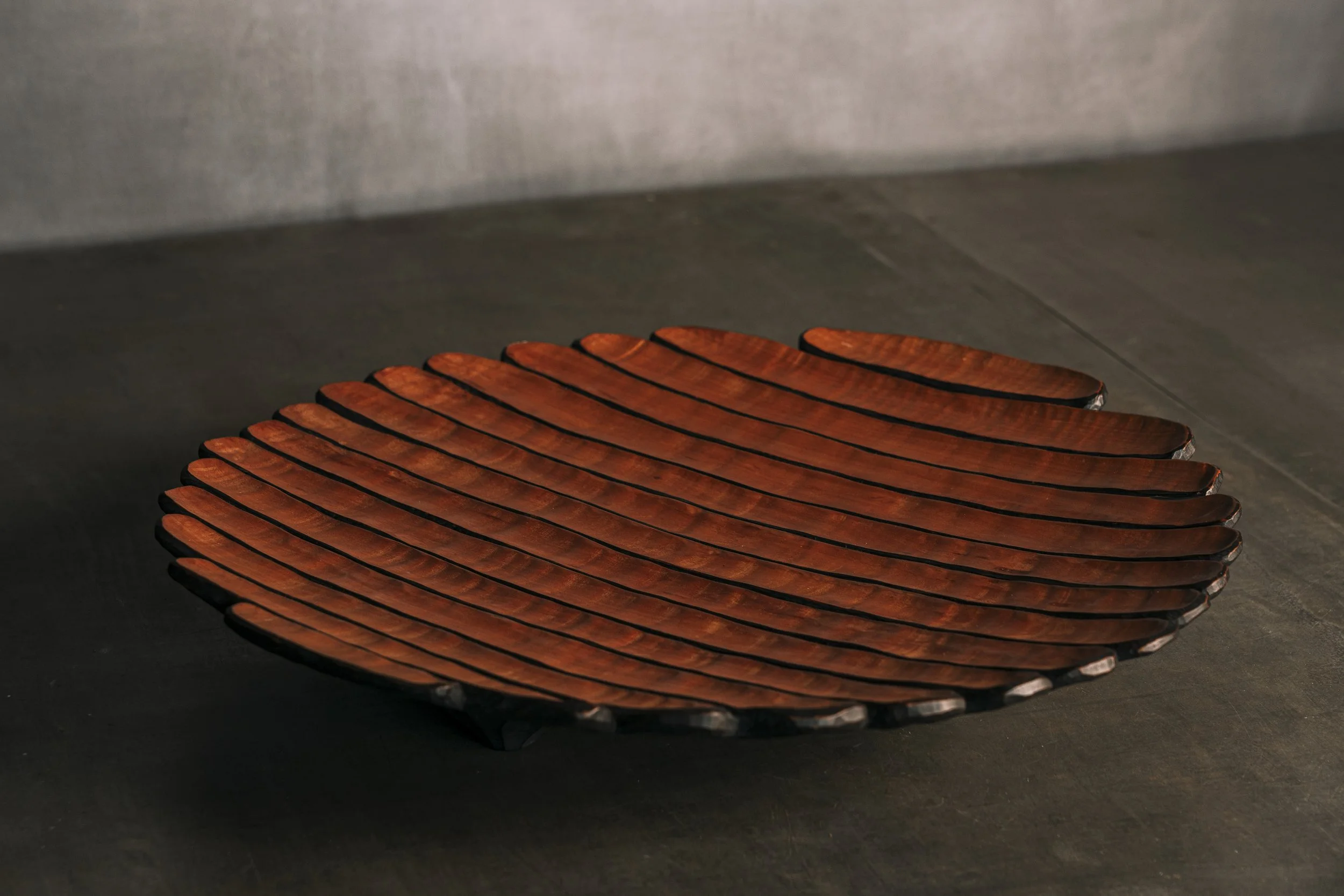 Runde, flache Holzschale mit einer Struktur aus Hohlkehlen und schwarzen Rillen. Birnbaumholz. Sehr dekorativ . Interiordesign.