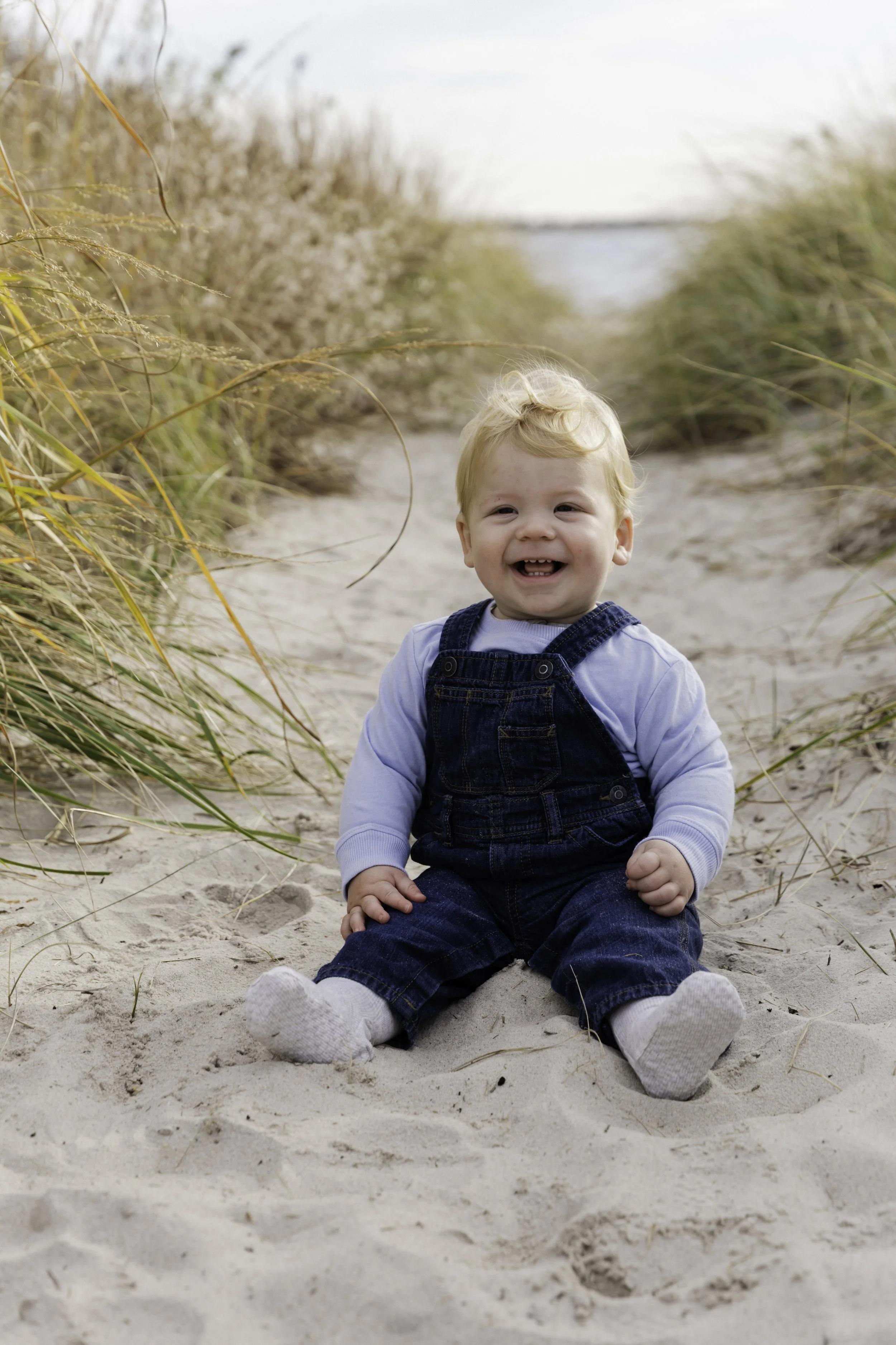 Smiling toddler on sandy trail with tall grass — New York City family portrait