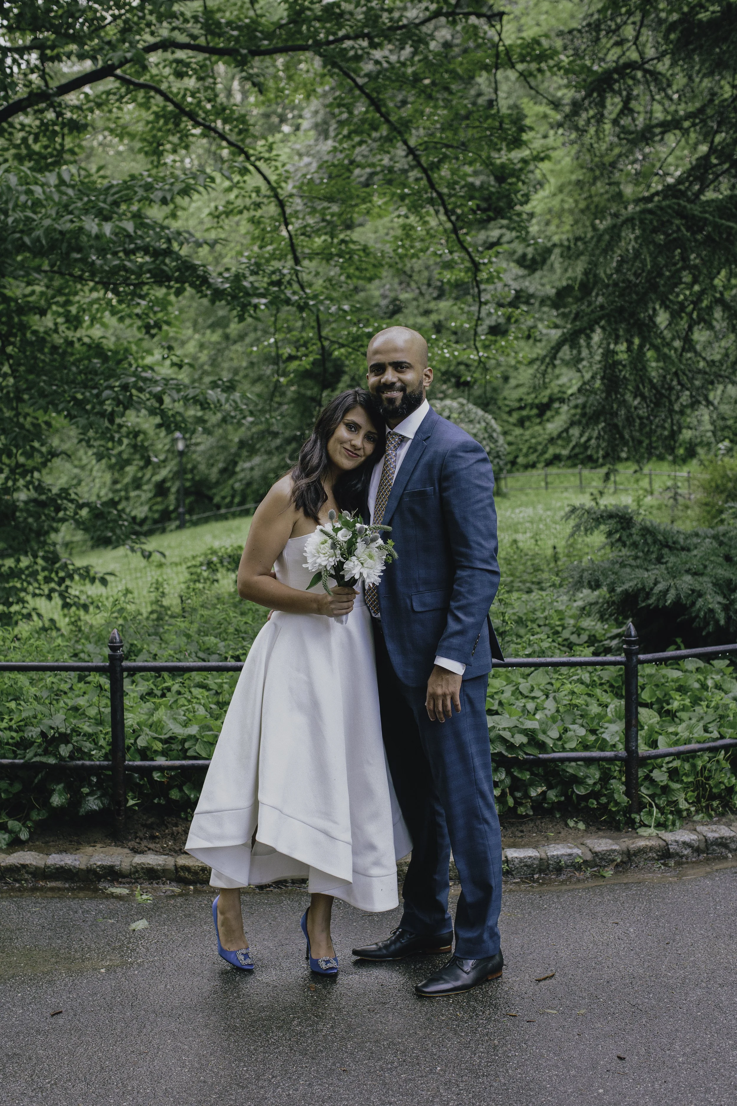 A newlywed couple standing on a paved path in a central park. NYC wedding photography