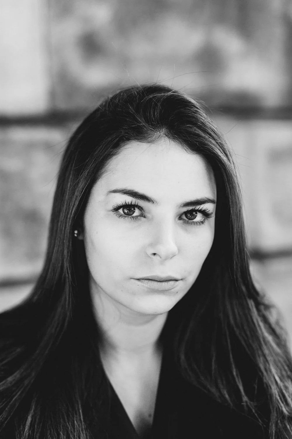 Black and white portrait of a young woman with long dark hair and expressive eyes, looking directly at the camera.