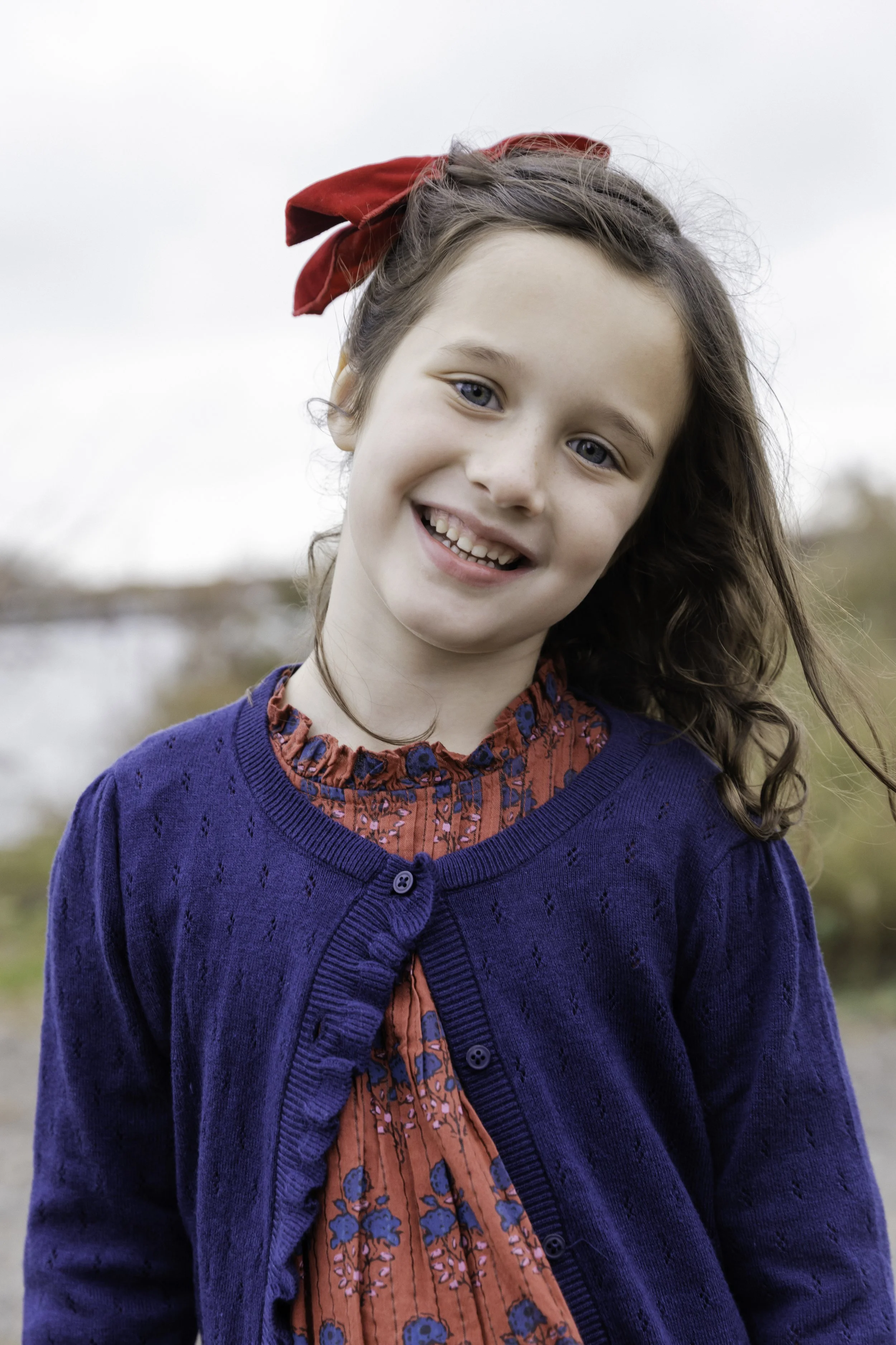 Young girl in floral dress with red bow outdoors — NYC family lifestyle photography