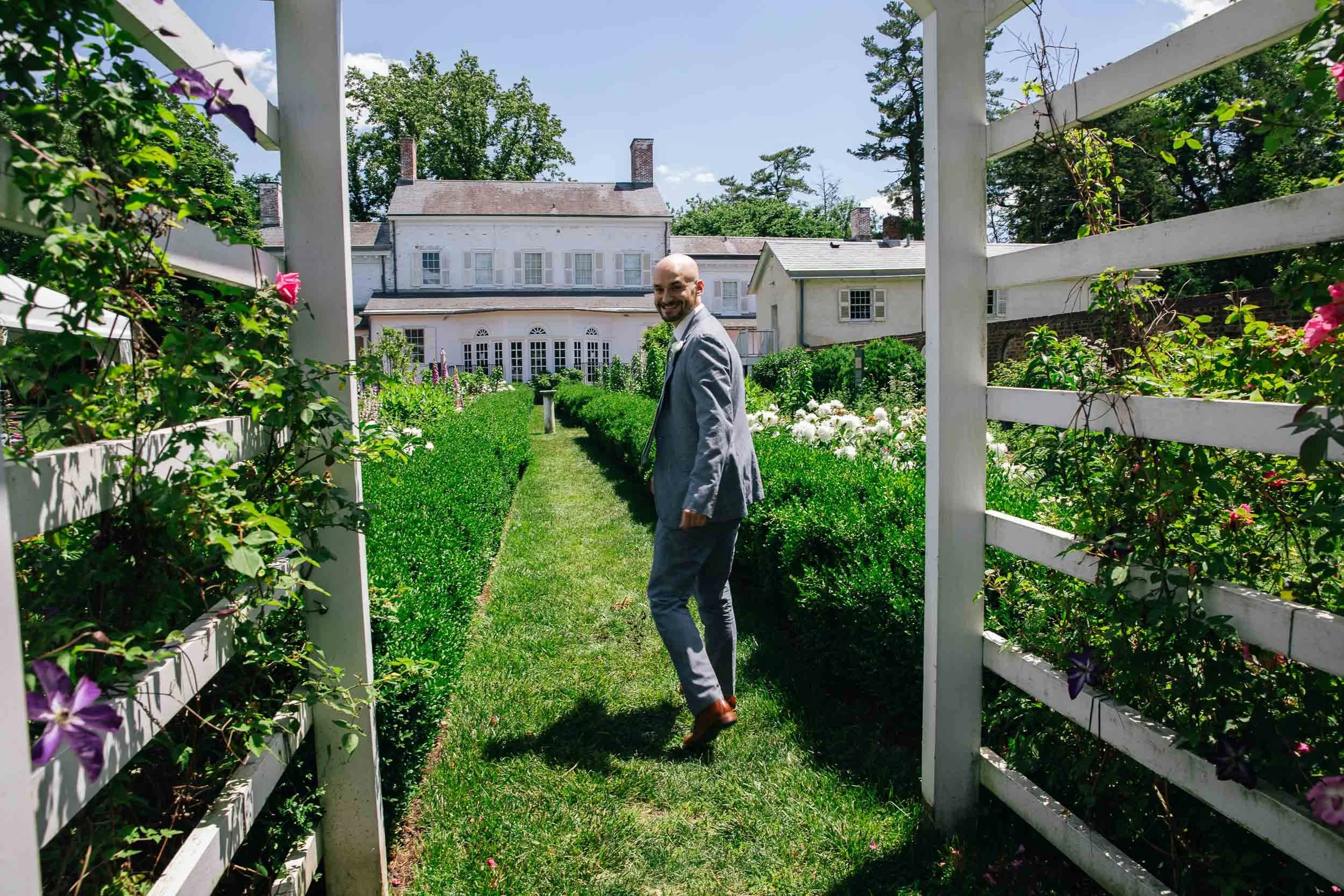 Groom smiling in lush garden during New York City wedding — documentary wedding photography NYC