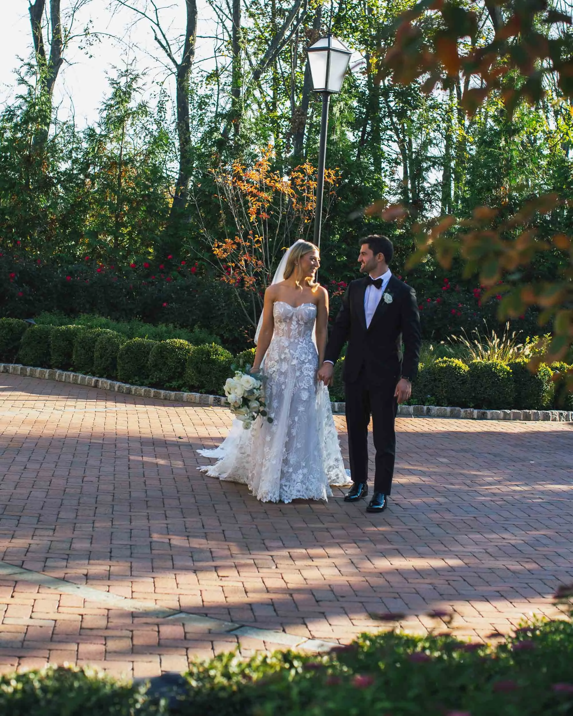Bride and groom walking on brick path during New York City wedding — emotional wedding photographer NYC
